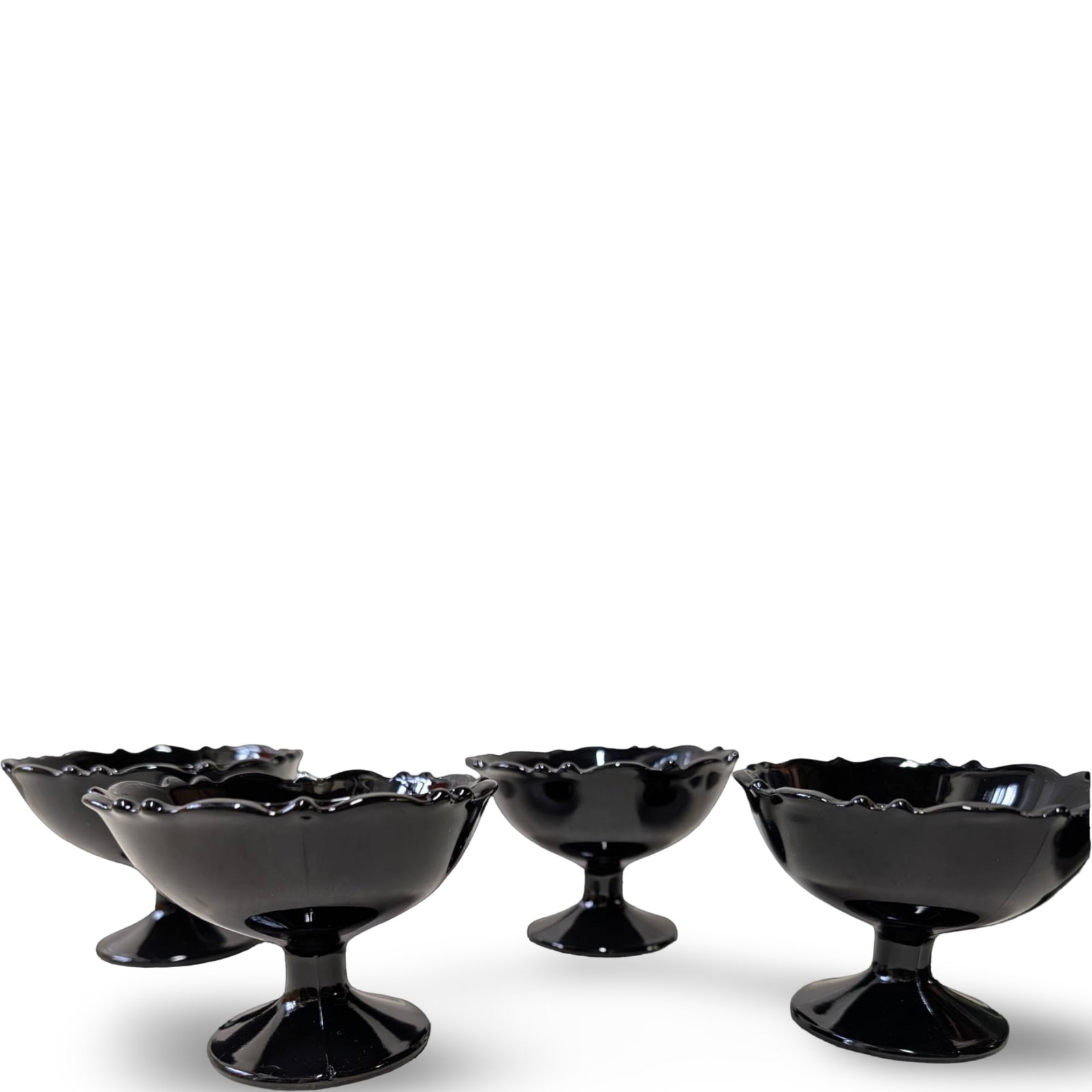 Four Black Amethyst Glass Pedestal Compotes: Four black amethyst glass pedestal compotes, each measuring approximately 4 inches in diameter and 3 inches in height. Featuring scalloped rims and sturdy pedestal bases, these glasses exhibit a gloss