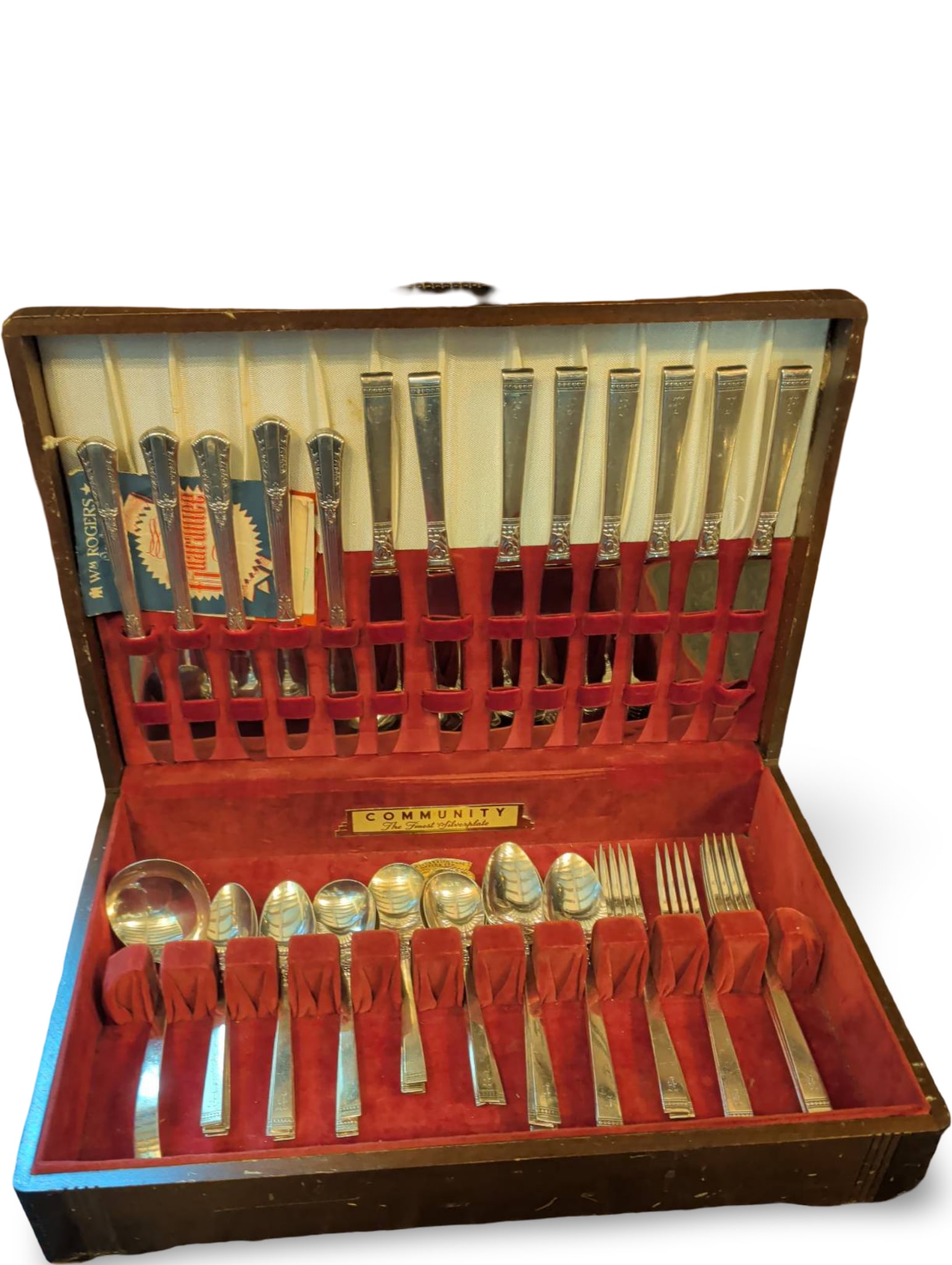 Wooden Flatware Chest with Stainless Steel Utensils: A wood flatware storage chest containing a set of stainless steel flatware in a velvet-lined interior. The set includes knives, forks, spoons, and serving utensils. The chest features a hinged lid and