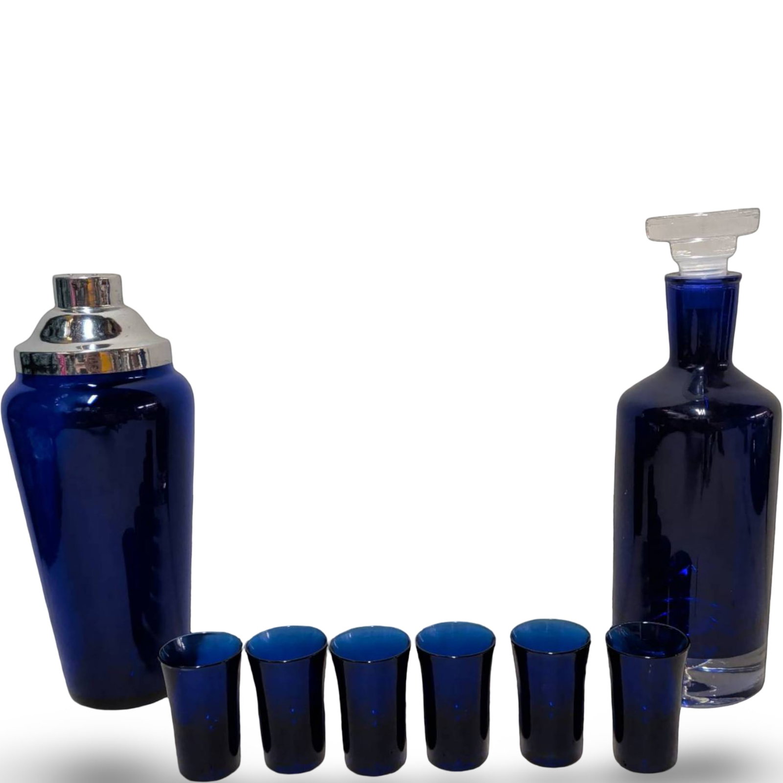 Cobalt Blue Decanter with Stopper, Shaker, and Six Shot Glasses: A cobalt blue decanter with stopper (11 1/2 in. tall), a cocktail shaker with chrome-tone lid (10 1/2 in. tall), and six matching cobalt blue shot glasses (each 2 3/4 in. tall). The glassware features