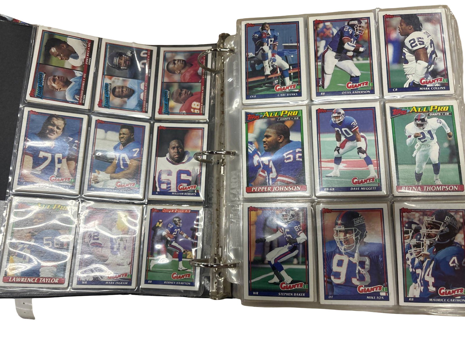 Binder of Football Trading Cards, Various Players and Teams: Football trading cards mounted in plastic sleeves inside a black binder. Cards feature various players and teams from different years and manufacturers, including recognizable brands such as Topps and