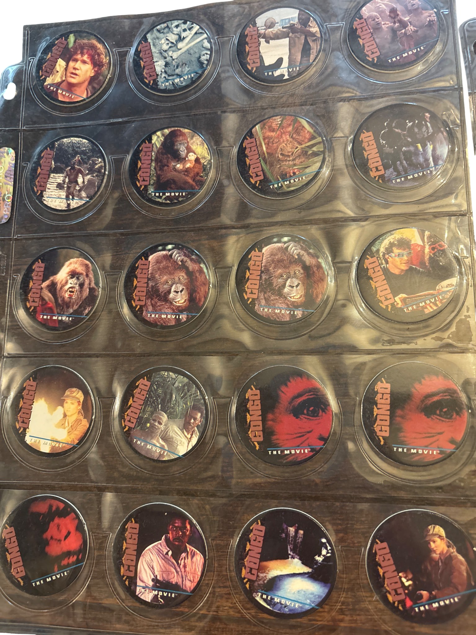 Complete Set of ‘Pog 1-39’ Congo Caps Featuring ‘Congo: The Movie’: Complete set of 39 collectible 'Congo: The Movie' pogs. Encased in a clear plastic display sleeve, each pog features a colorful image from the 1995 movie on one side, and numbered text details on the 