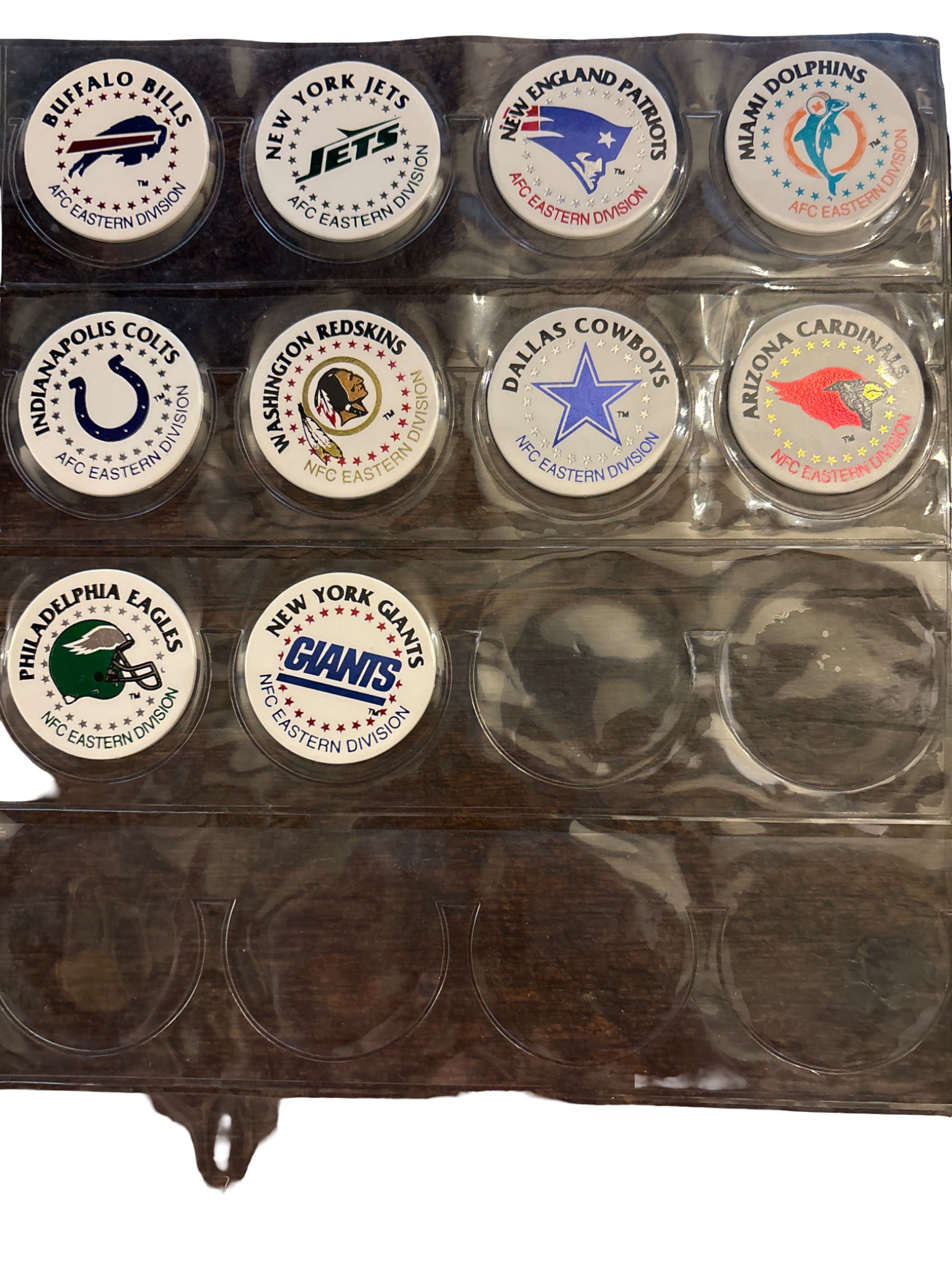 1995 NFL Team Pogs by Laserform, Complete Set in Plastic Album: 1995 NFL Team Pogs by Laserform featuring logos of 30 football teams in their divisions at the time. Includes a protective plastic album for storage. The reverse side of each pog is marked with the