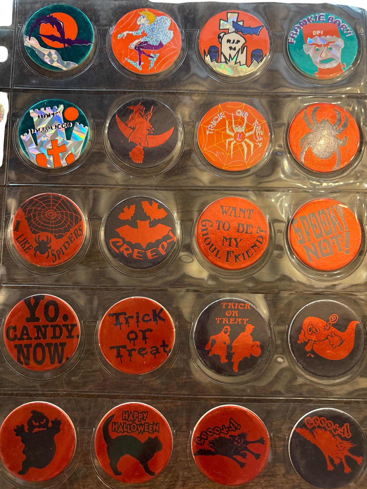 Halloween-Themed Pog Milk Caps in Plastic Sleeves: Round pog milk caps featuring Halloween-themed graphics, including pumpkins, skeletons, bats, and ghostly imagery. Caps are housed in transparent plastic sleeves for display and preservation. Designs 