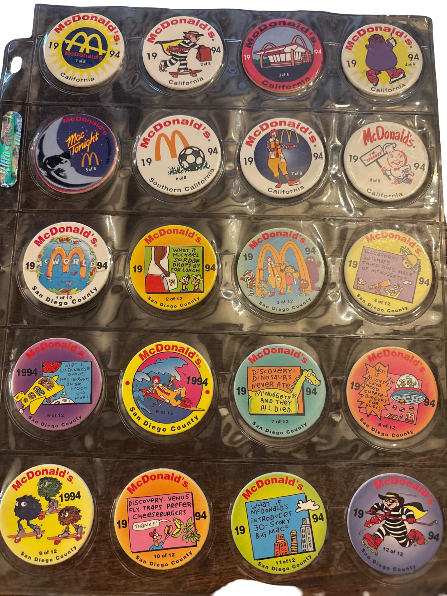 20 McDonald’s 1994 Pogs in Plastic Display Sheets: 20 McDonald's promotional Pogs from 1994, each featuring colorful designs and a variety of themes, including California landmarks, characters, and promotional graphics. The reverse side features a