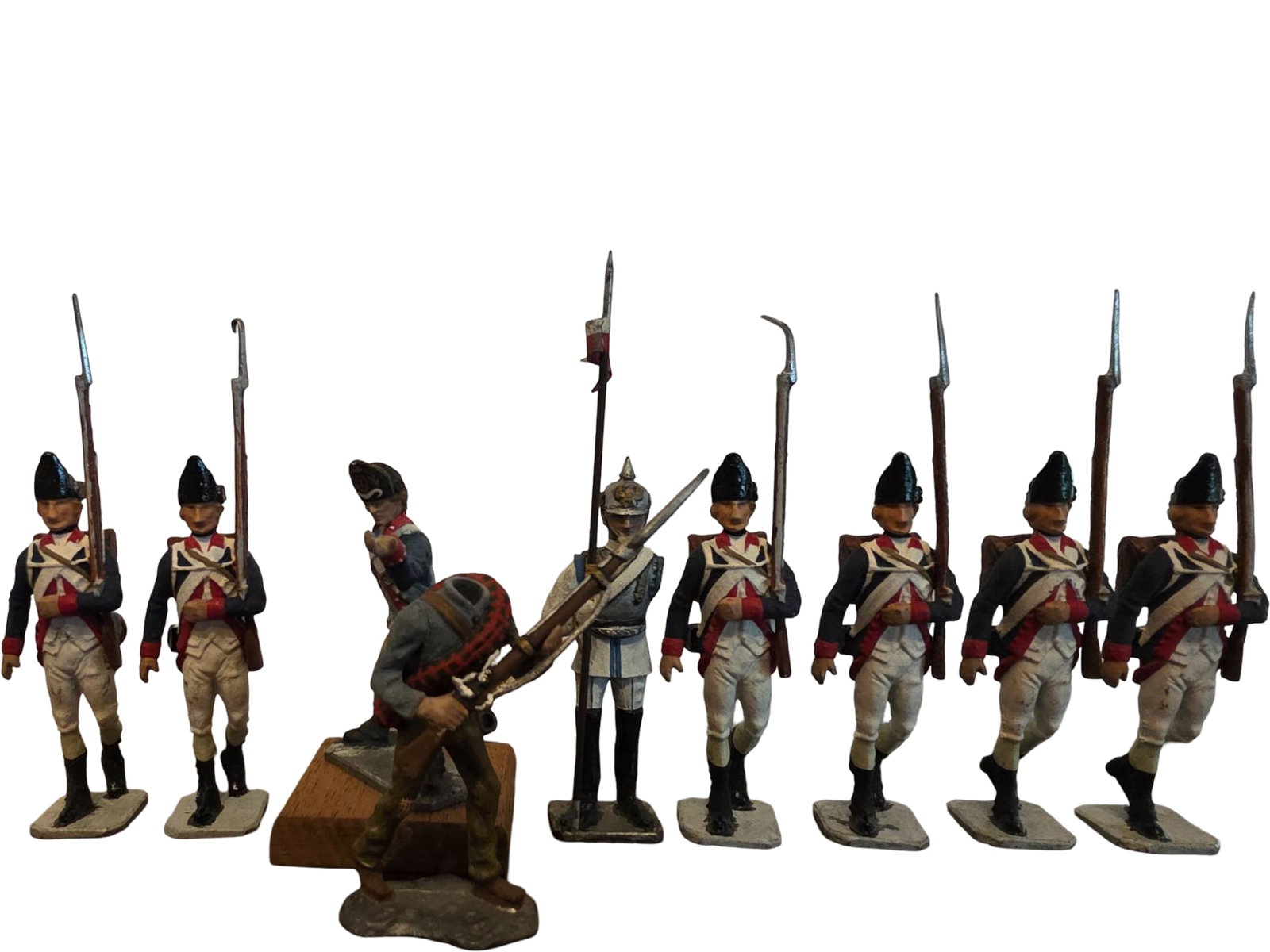Painted Metal Military Figurines, Nine Soldiers in Various Uniforms: Nine painted metal military figurines depicting soldiers in various historical uniforms. Eight stand on rectangular bases, and one custom base is wooden. The soldiers feature rifles, bayonets, and int