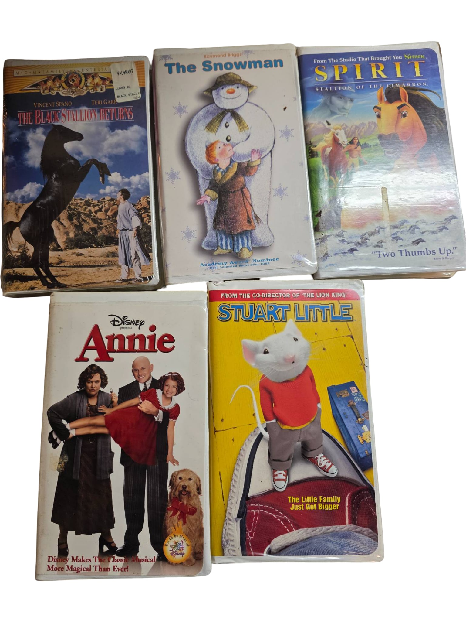 Five Children’s VHS Tapes Featuring Animated and Live-Action Titles: Five children’s VHS tapes, including “The Black Stallion Returns,” “The Snowman,” “Spirit: Stallion of the Cimarron,” “Annie” (Disney), and “Stuart Little.”