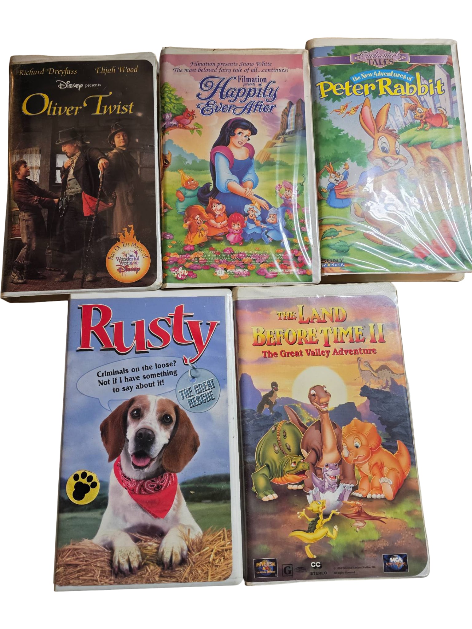 Five VHS Tapes Featuring Animated and Thematic Content: Five VHS tapes, including titles Oliver Twist,Snow White Happily Ever After, Peter Rabbit,Rusty: The Great Rescue, and The Land Before Time II: The Great Valley Adventure.” The tapes come in