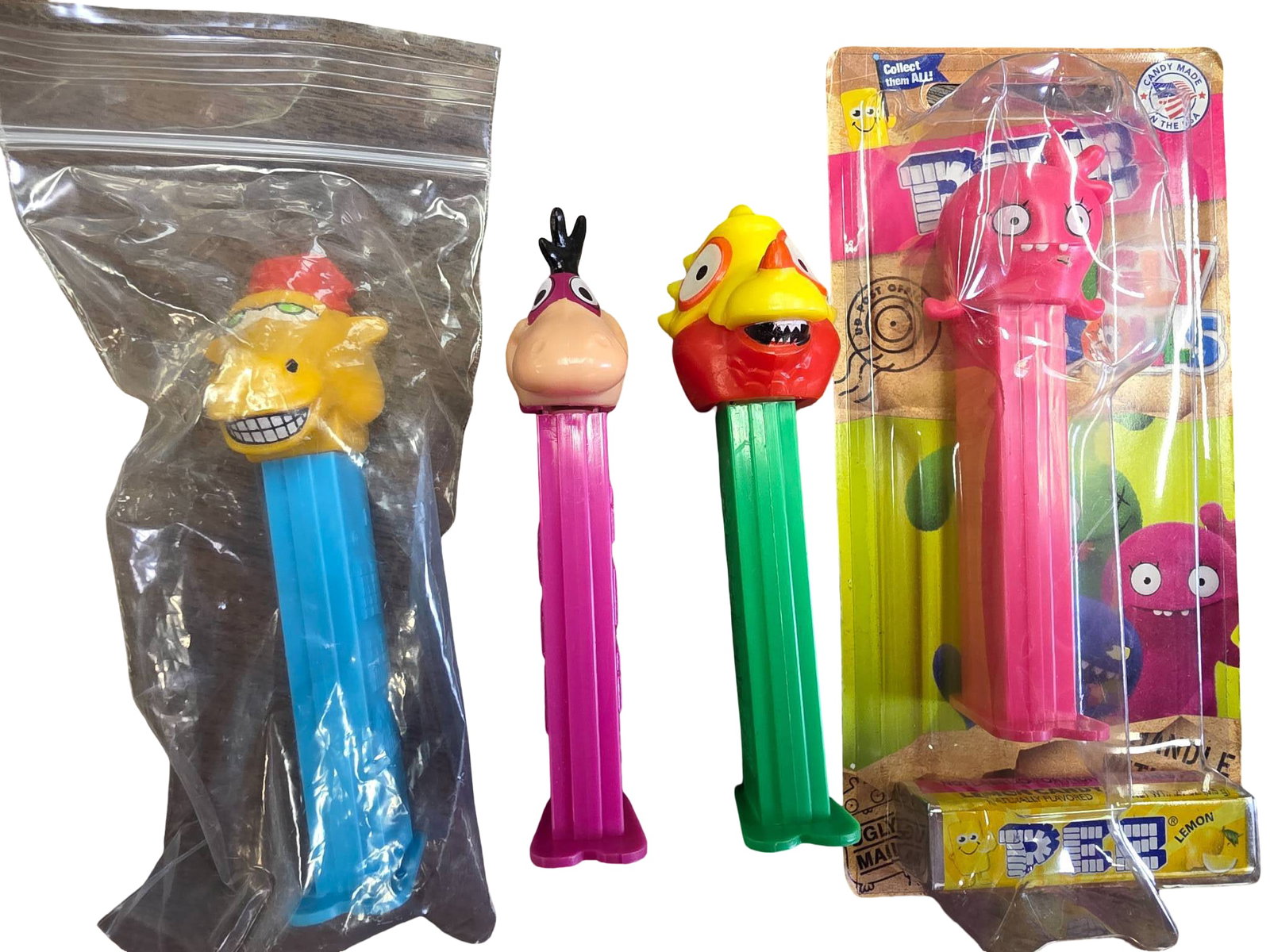 Four Cartoon Character PEZ Dispensers: Four PEZ candy dispensers depicting various cartoon characters. Includes two dispensers in opened condition, one in sealed plastic wrap, and one mounted on its original carded packaging. Brightly colo