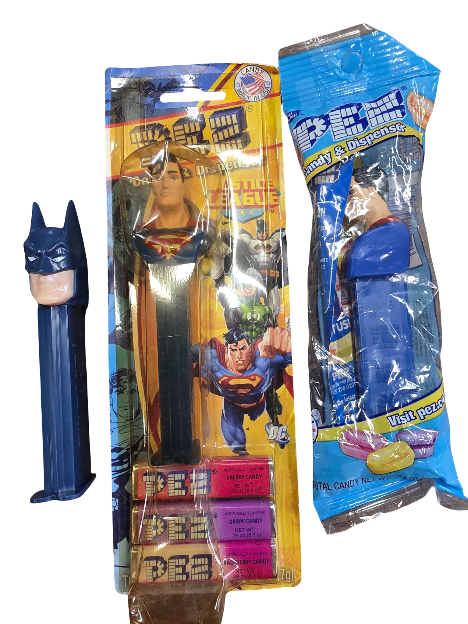 Justice League PEZ Candy Dispensers: Superman and Batman: Three Justice League PEZ candy dispensers, including Superman (in original unopened packaging with PEZ candy included) and Batman (unwrapped, loose). Both dispensers are plastic and feature character 