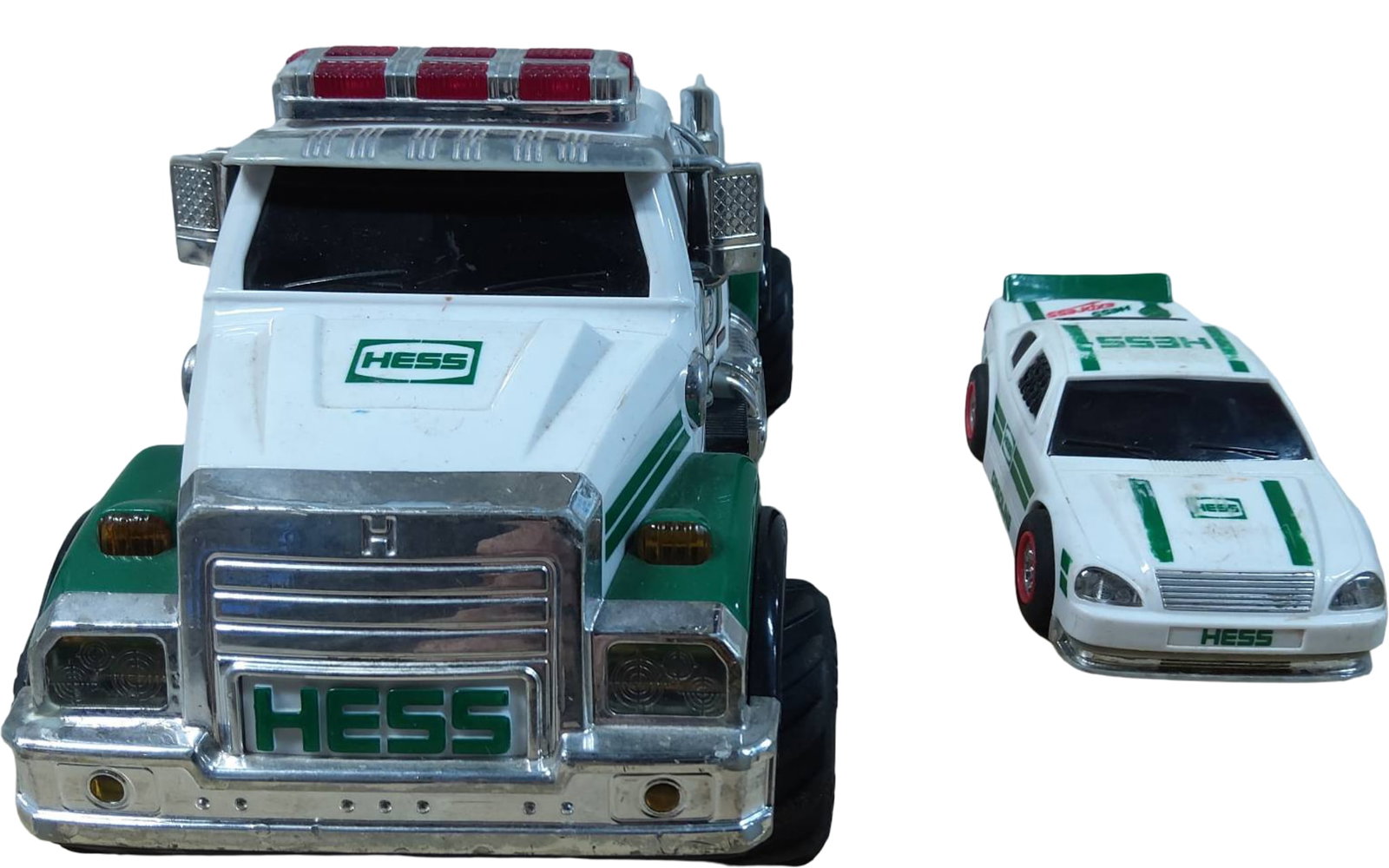Hess Toy Truck and Race Car Set with Lights: Hess toy truck and race car set featuring a white and green design with Hess branding. The truck includes light-up features and is paired with a smaller race car design. Both vehicles are made of mold