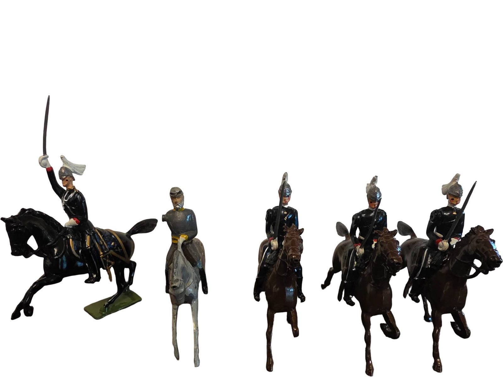 Five Painted Lead Toy Soldiers on Horseback: Five painted lead toy soldiers, each mounted on a horse in a variety of poses. Four soldiers wear black uniforms with helmets and plumes, while one figure has different attire, featuring a grey