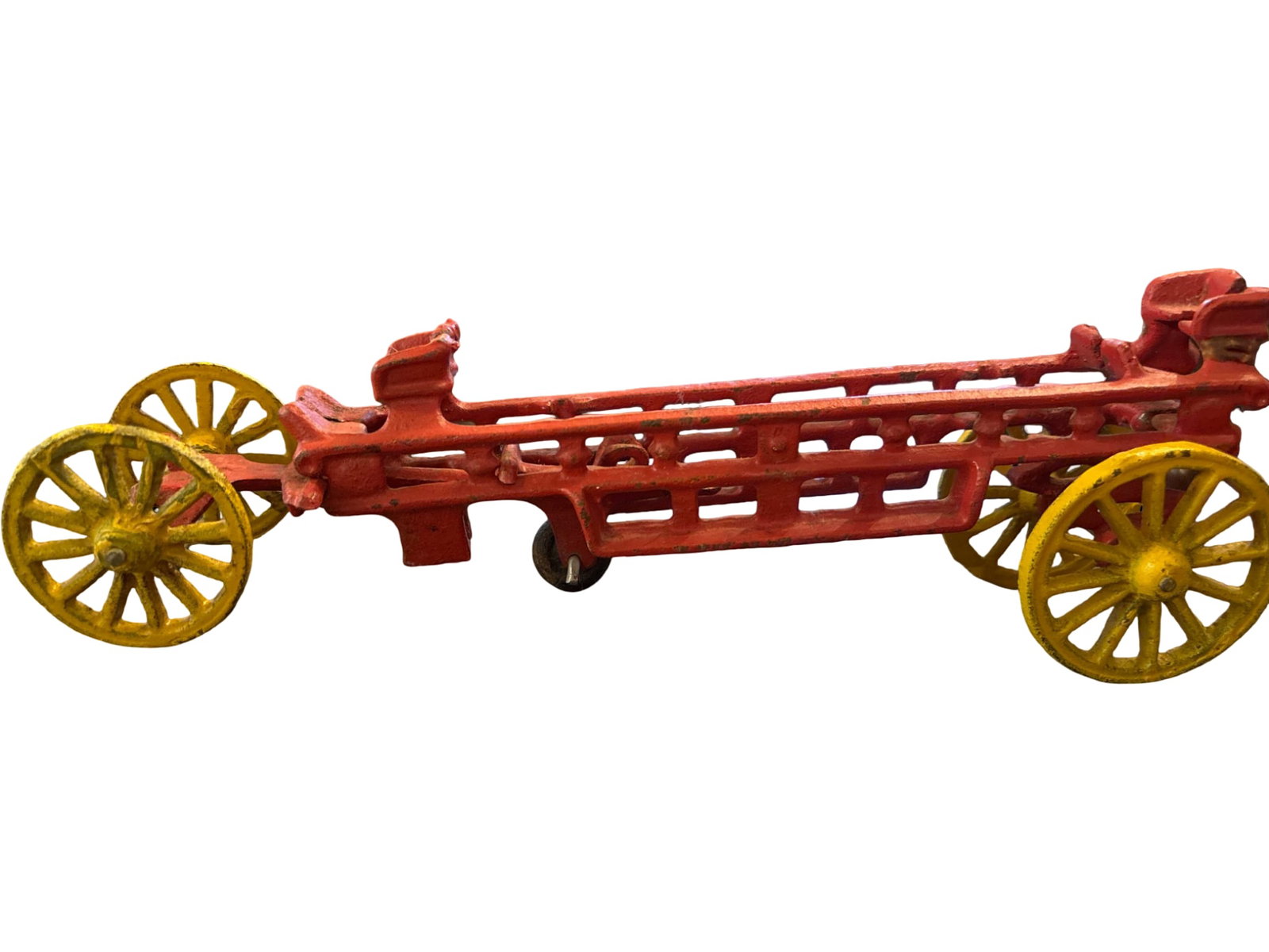 Cast Iron Red Hose Cart Toy with Yellow Spoked Wheels: Cast iron toy hose cart featuring a red-painted frame with openwork details and yellow spoked wheels. The piece is designed to resemble horse-drawn fire apparatus from the late 19th to early 20th cent
