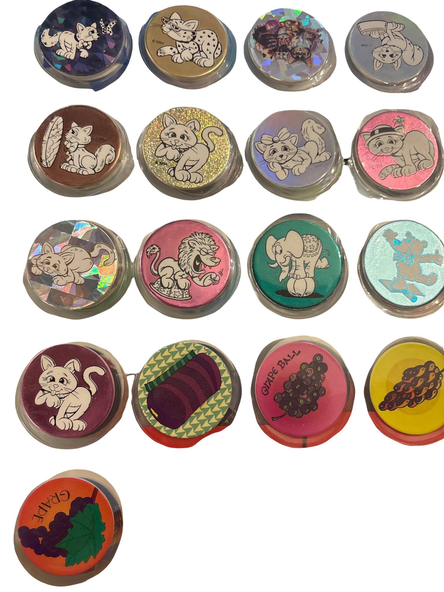 Pogs with Holographic and Printed Cat Designs: Pogs featuring various prints, including holographic designs and themed cat graphics. Includes vibrant designs such as kittens, fruits, and textured patterns. Pogs are displayed in a plastic sleeve