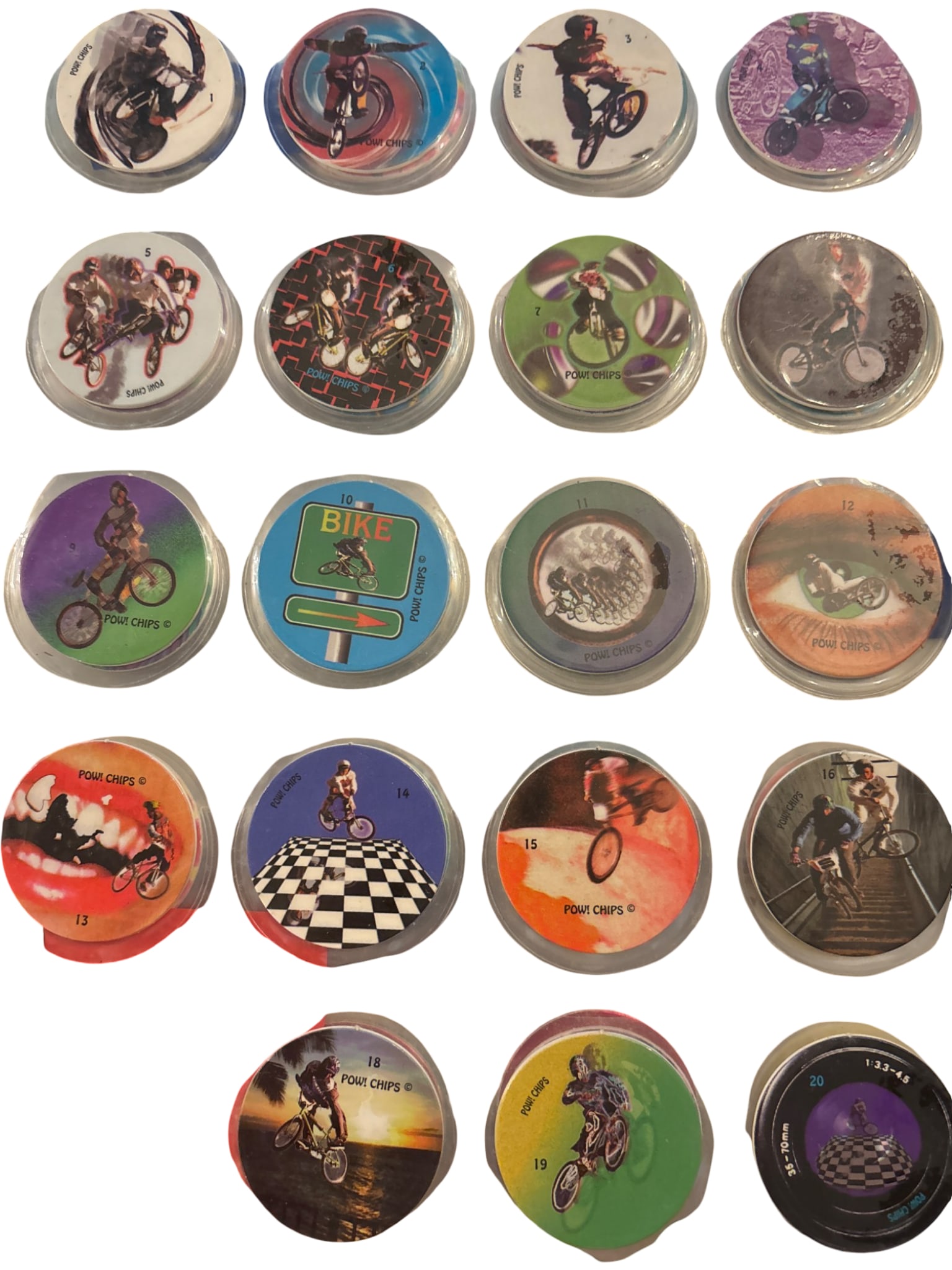 Pog ‘POW! Chips’ 1-20, Missing #17: Pog 'POW! Chips' numbered 1-20, with #17 missing. Each chip features vibrant graphic designs, primarily themed around bicycling and stunts. The chips are housed in a clear plastic sleeve for