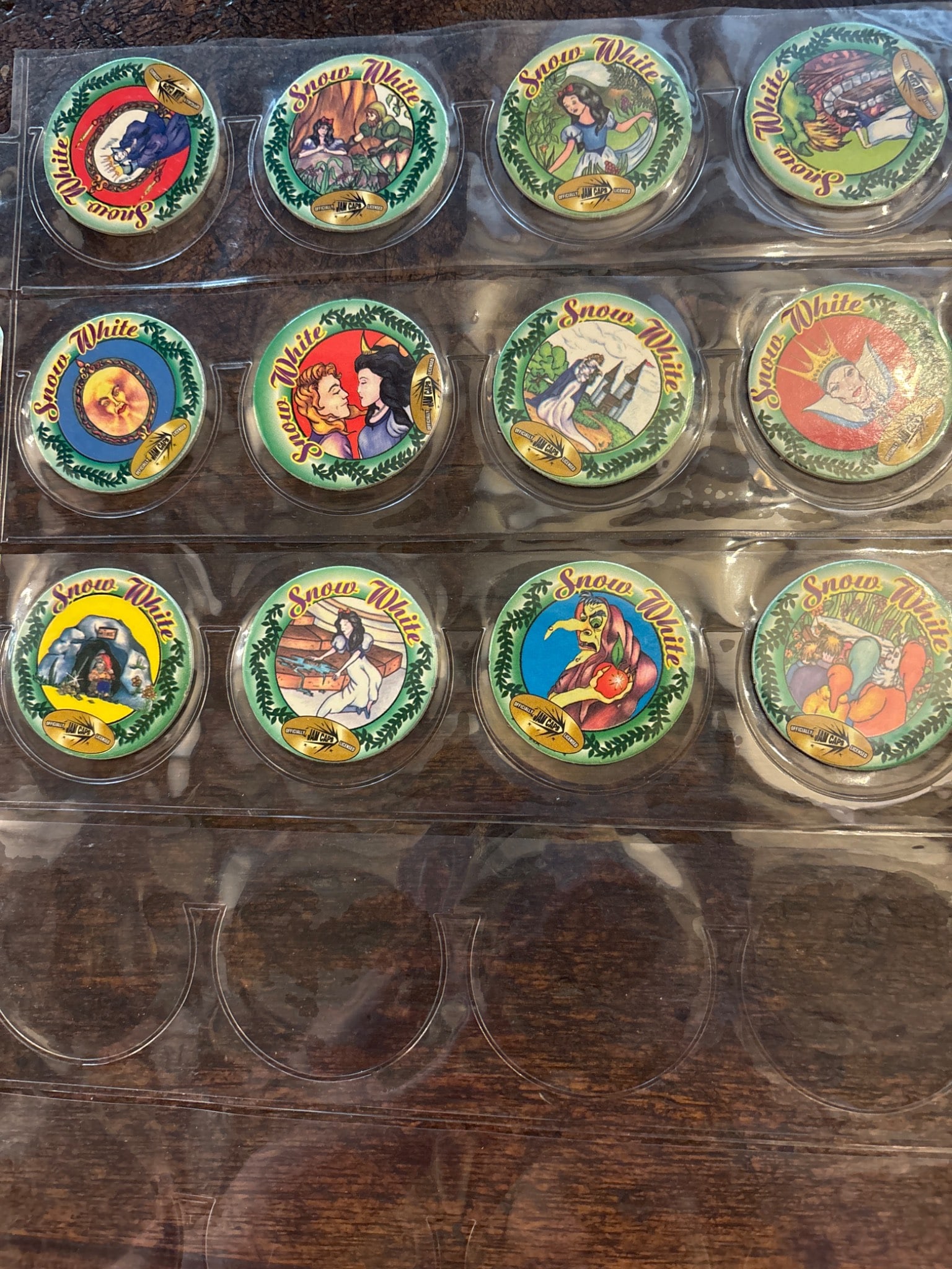 Snow White-Themed Pogs in Protective Display Case: Snow White-themed Pogs featuring vibrant depictions of characters and scenes from the Snow White story. Includes 12 individual Pogs displayed in a clear plastic protective case. Each Pog is marked wit
