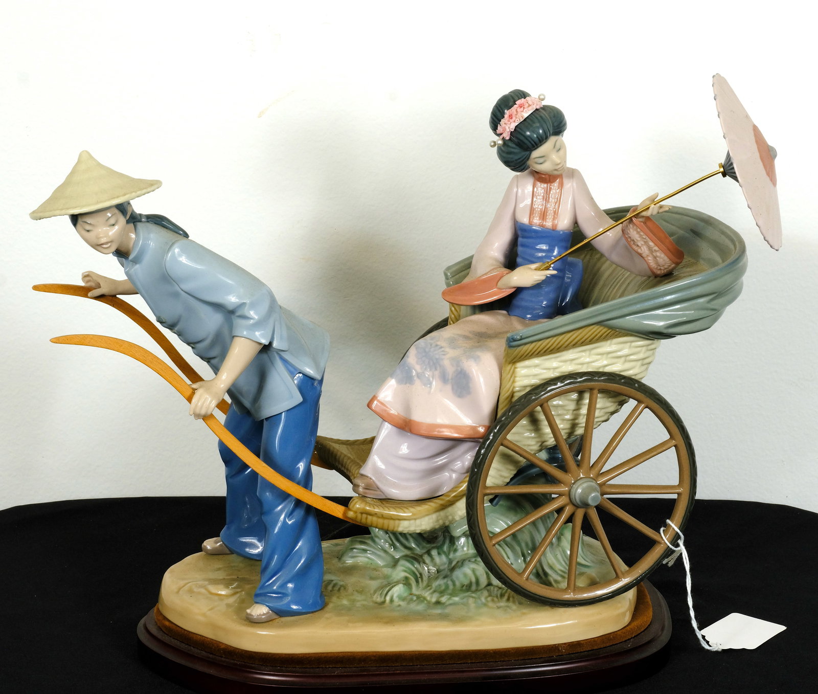 Lladro Lady in Rickshaw: Vintage porcelain Lladro Lady in Rickshaw H 11 5/8 x W 16 in. (Figure w/o wood base) H 12 3/4 x W 16 in. (Figure w/ wood base)