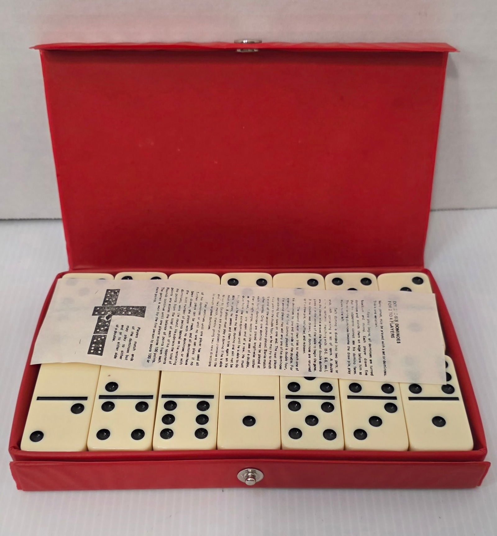 1980s Cardinal Domino Set in Red Case: Vintage 1980s Cardinal boxed domino set in original red case. Includes dominoes and interior paperwork insert as shown. Case shows light wear consistent with age. Complete as photographed.