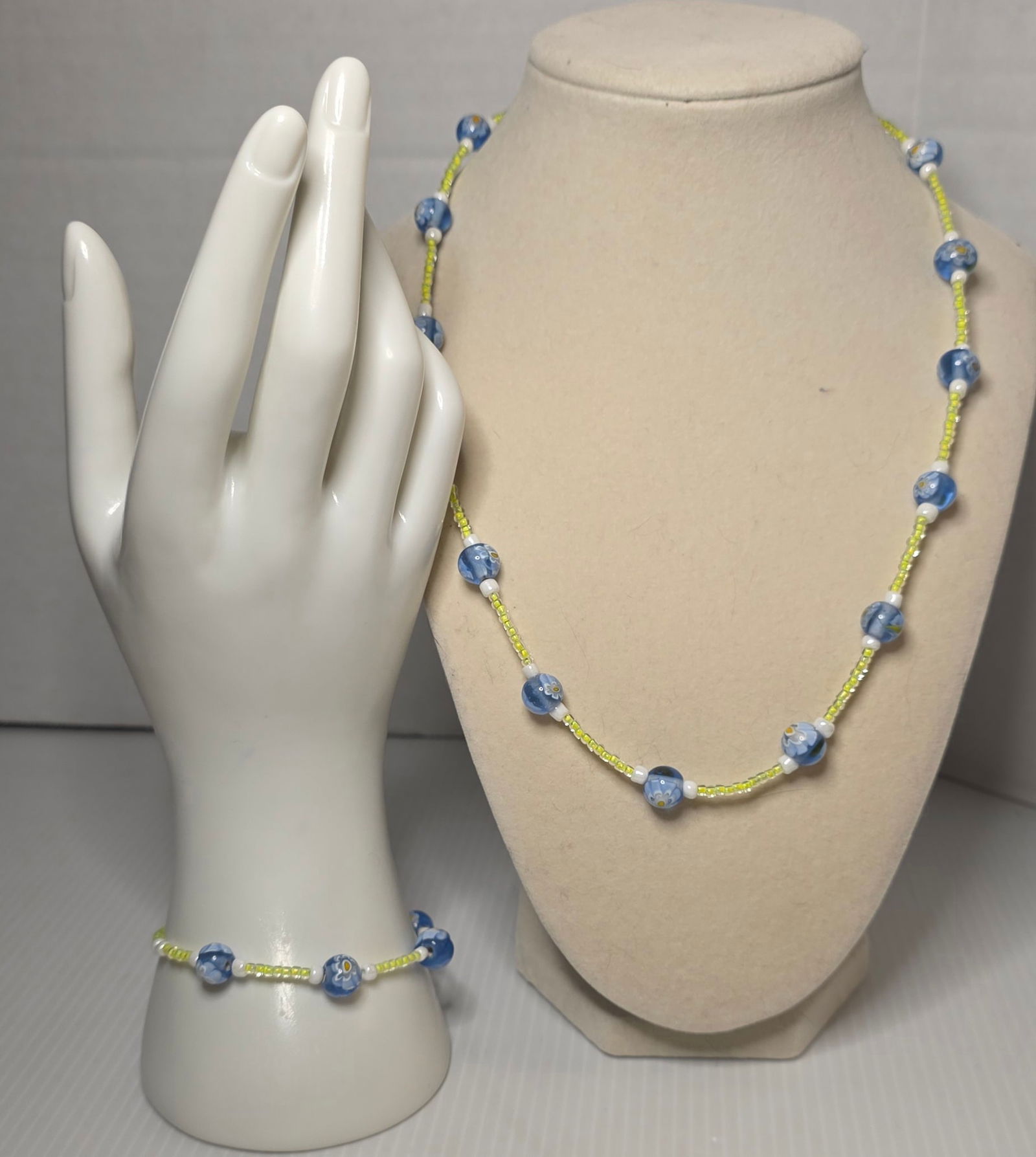 Vintage Beaded Necklace Bracelet Set Blue Floral Glass Beads Matching: Vintage matching necklace and bracelet set featuring round blue floral glass appearance beads accented with yellow seed beads and white spacer beads. Silver tone lobster clasp closures. Necklace measu