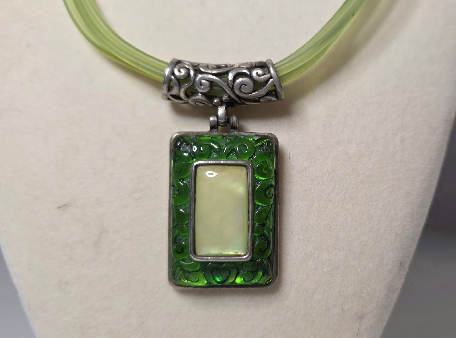 Vintage Green Jelly Tube Necklace Mother of Pearl Style Pendant Statement: Vintage statement necklace featuring translucent green jelly style multi strand tube cord with silver tone decorative accents. Rectangular pendant with green translucent border and center mother of pe