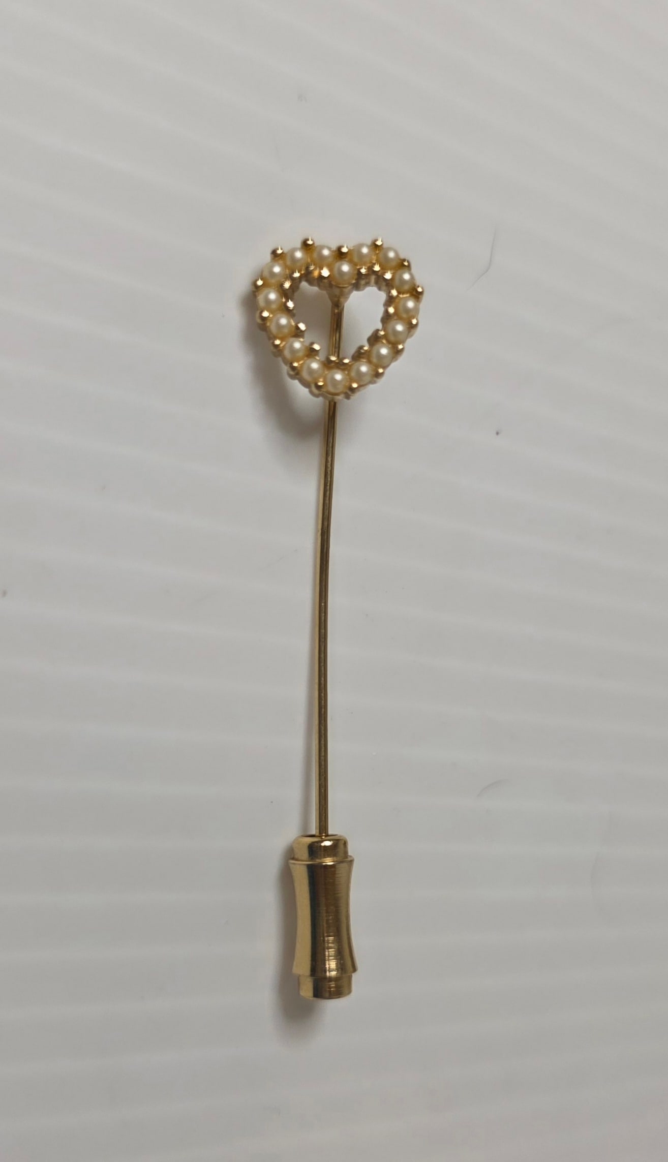 Heart Faux Pearl Stick Pin Gold Tone Hat Lapel Brooch: Gold tone stick pin featuring open heart design set with small faux pearl accents. Classic hat pin or lapel brooch style with protective end cap. Metal unmarked and not magnetic. Approximate length 2.
