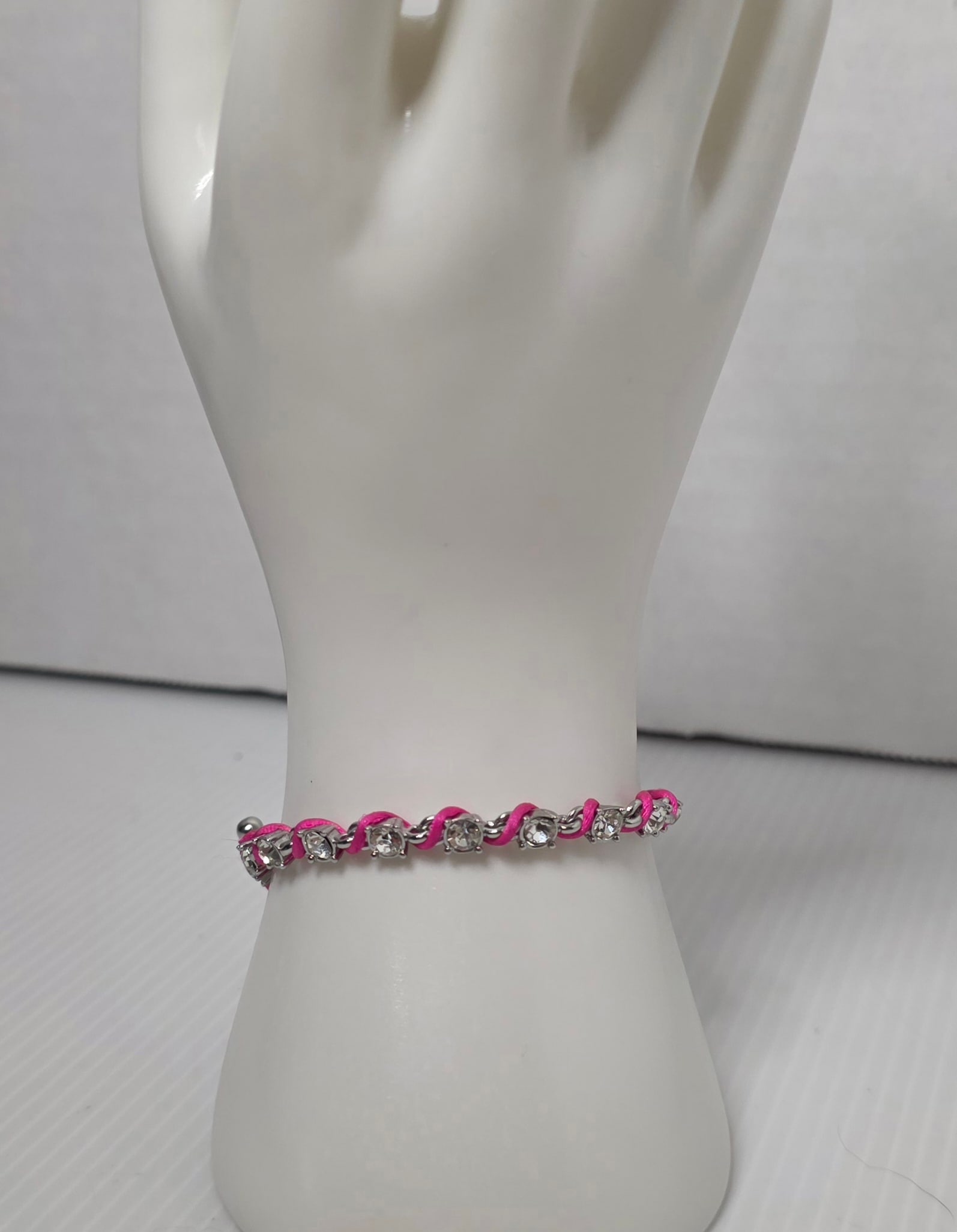 Ann Taylor Rhinestone Pink Cord Toggle Bracelet: Ann Taylor silver tone rhinestone bracelet with bright pink cord wrap detail. Clear round rhinestones set along chain with toggle clasp closure. Rhinestone charm drop accent. Measures approximately 7.
