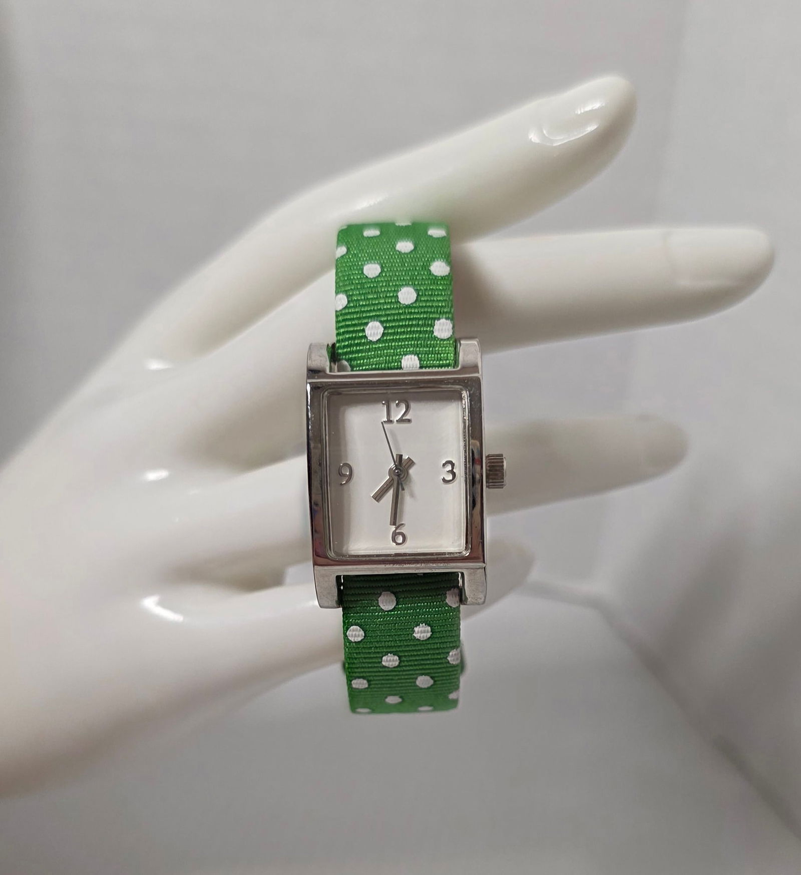 Bath & Body Works Holiday Limited Release Polka Dot Watch: Bath & Body Works limited holiday release wristwatch with rectangular silver tone case and white dial. Arabic numerals at 12, 3, 6, and 9. Green fabric strap with white polka dot pattern and genuine l