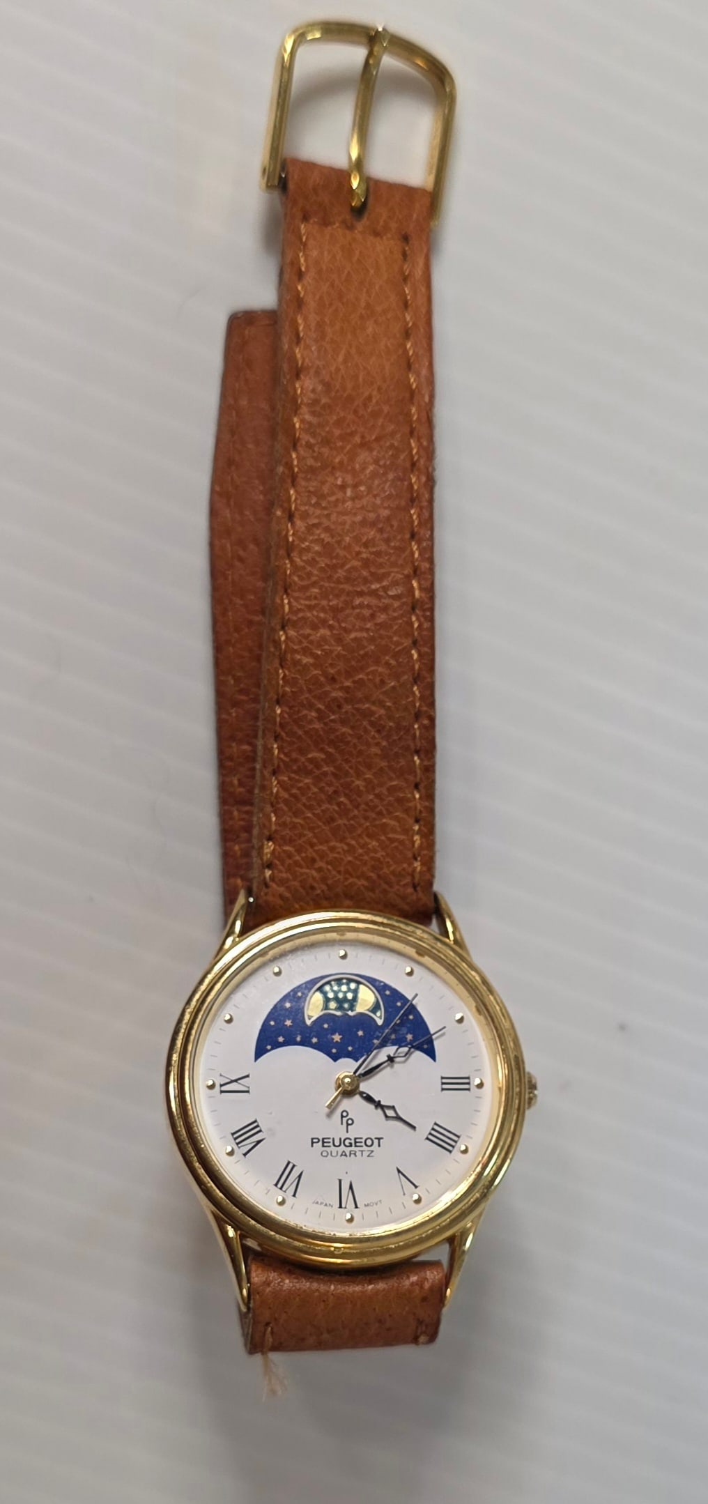 Vintage Peugeot Moonphase Quartz Womens Watch Gold Tone: Vintage Peugeot quartz women’s wristwatch with moonphase style dial. White face with Roman numerals, gold tone case, and blue moon and star display. Dial marked Peugeot Quartz with Japan movt.Stainl