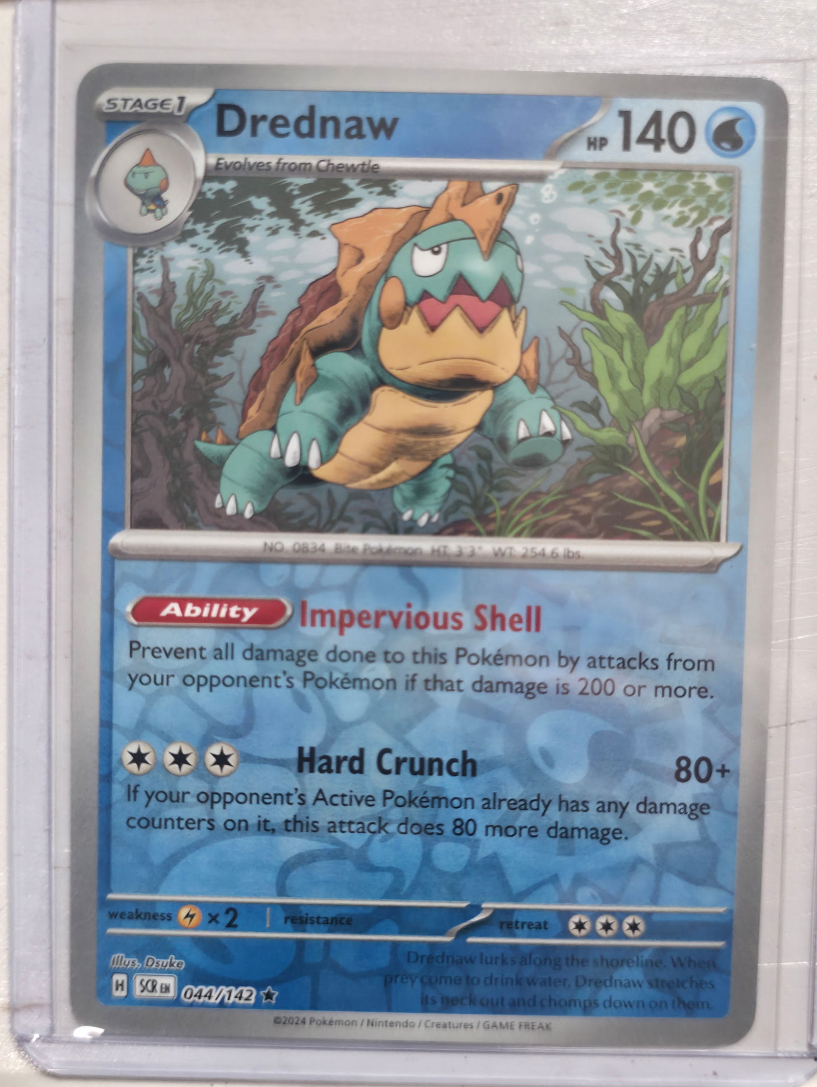 2024 Drednaw Stellar Crown 044/142 Reverse Holo: 2024 Drednaw Stage 1 Water Pokemon. Evolves from Chewtle. Stellar Crown set. Card number 044/142. Reverse holo with reflective pattern in text area. HP 140. Ability Impervious Shell. Attack Hard Crunc