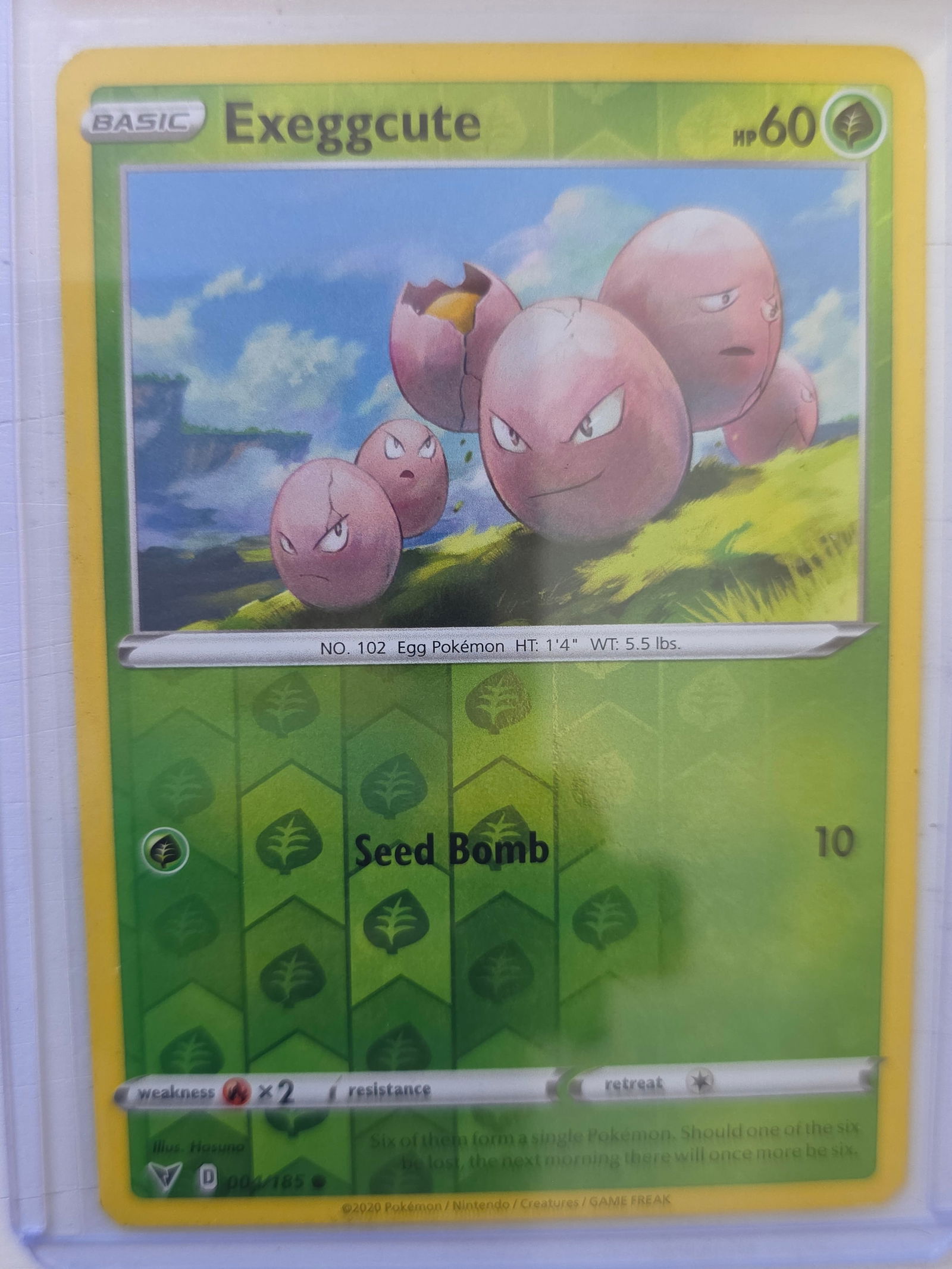2020 Exeggcute Vivid Voltage 004/185 Reverse Holo Pokemon Card: 2020 Pokemon Exeggcute reverse holo card numbered 004/185 from the Sword & Shield Vivid Voltage expansion set. Illustrated by Hasuno. Reverse holographic foil pattern across the card surface. Card sto