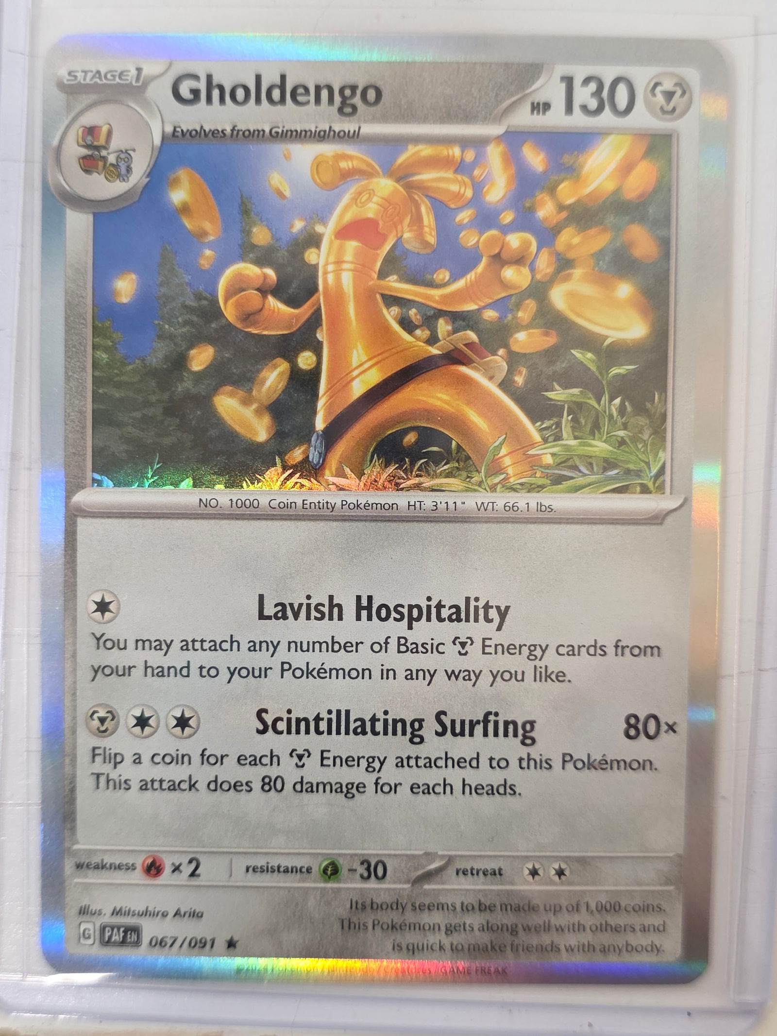 2024 Gholdengo Paldean Fates 067/091 Holo Pokemon Card: 2024 Pokemon Gholdengo holographic card numbered 067/091 from the Scarlet & Violet Paldean Fates expansion set. Illustrated by Mitsuhiro Arita. Standard holographic finish across the illustration area