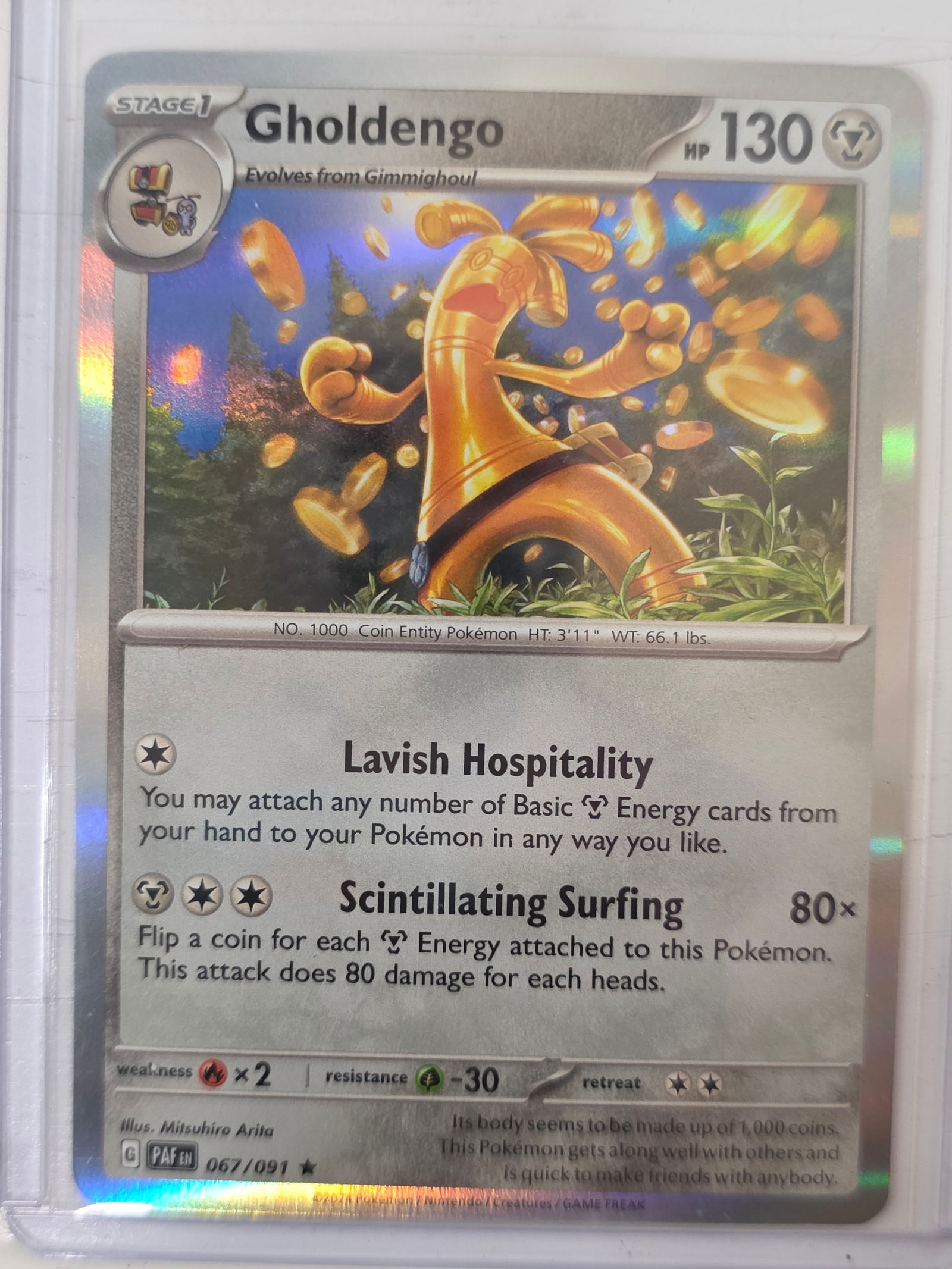 2024 Gholdengo Paldean Fates 067/091 Holo Pokemon Card: 2024 Pokemon Gholdengo holographic card numbered 067/091 from the Scarlet & Violet Paldean Fates expansion set. Illustrated by Mitsuhiro Arita. Standard holographic finish across the illustration area