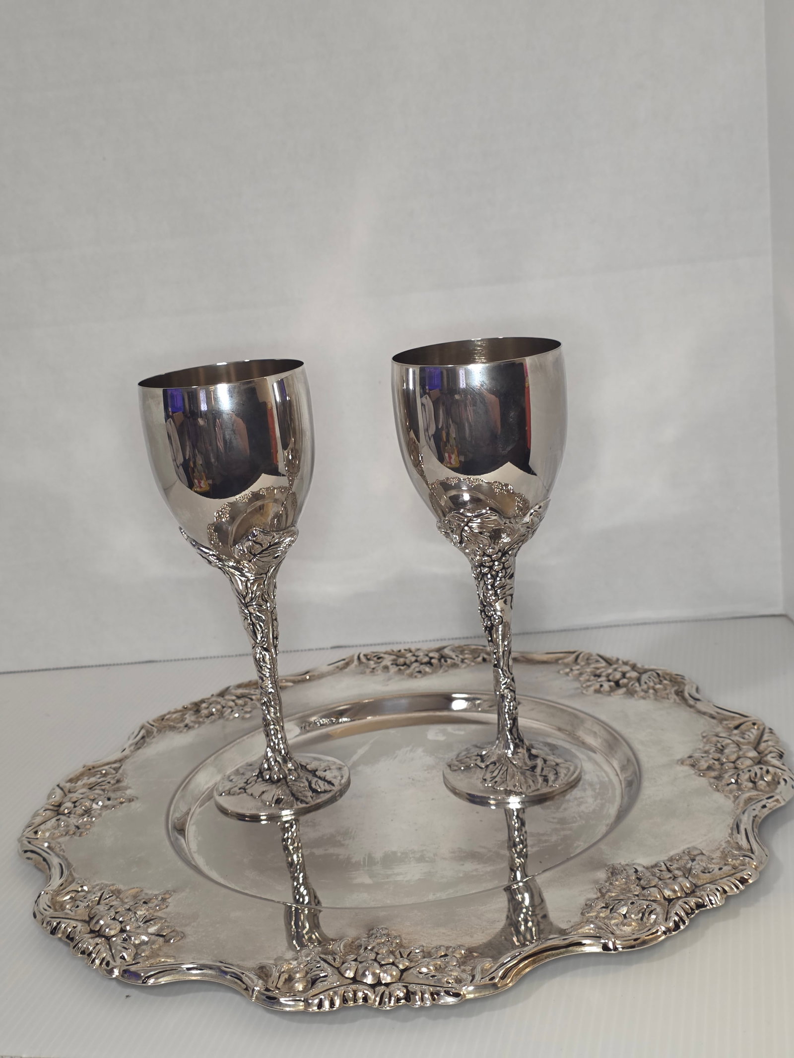 Godinger Silver Art Grapevine Tray Goblet Set 3 Pc Silverplate: Three piece Godinger Silver Art Company serving set featuring a grapevine motif. The set includes an ornate tray and two matching stemmed goblets.The tray has a decorative border with raised grape clu