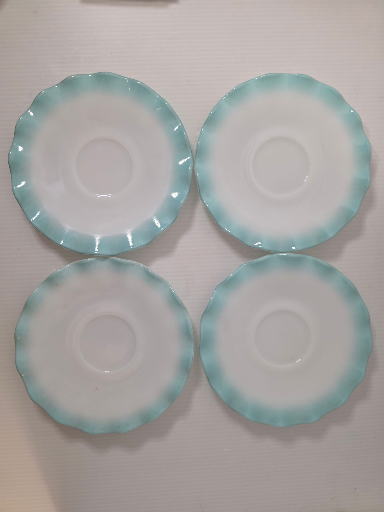 Vintage Milk Glass Saucers Aqua Blue Rim Scalloped Edge Set of 4: Set of four vintage milk glass saucers with aqua blue fade rim and scalloped edge design. Unmarked.Classic mid-century style suitable for teacups, display, or replacement pieces.All four show age-rela