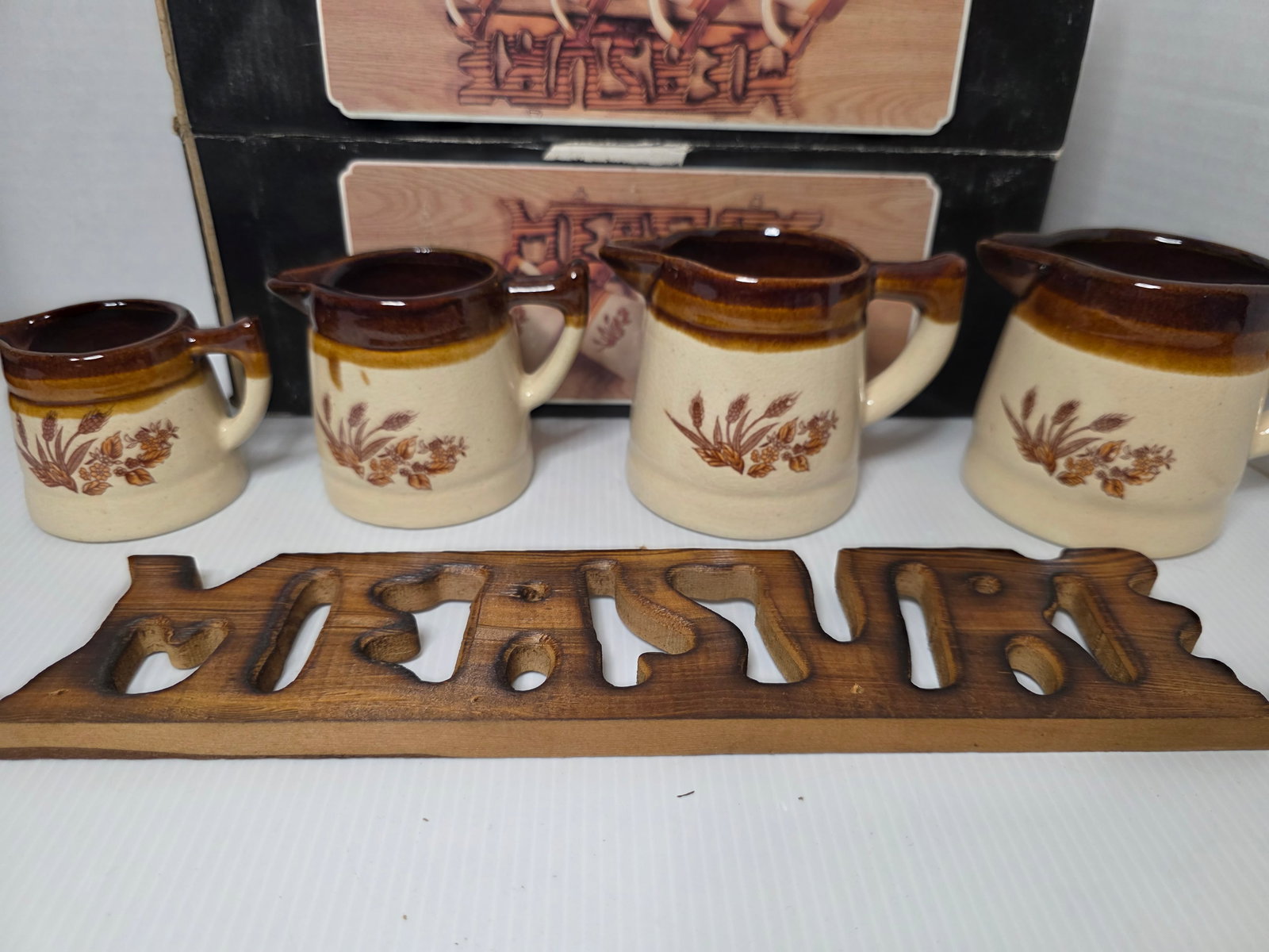 Giftco Ceramic Measuring Cup Set Wall Rack Wheat Pattern 4 Pc Boxed: Giftco ceramic measuring cup set with wall rack and original box. Includes four graduated measuring cups with spouts and handles. Features a beige and brown glaze with wheat motif and matching wooden