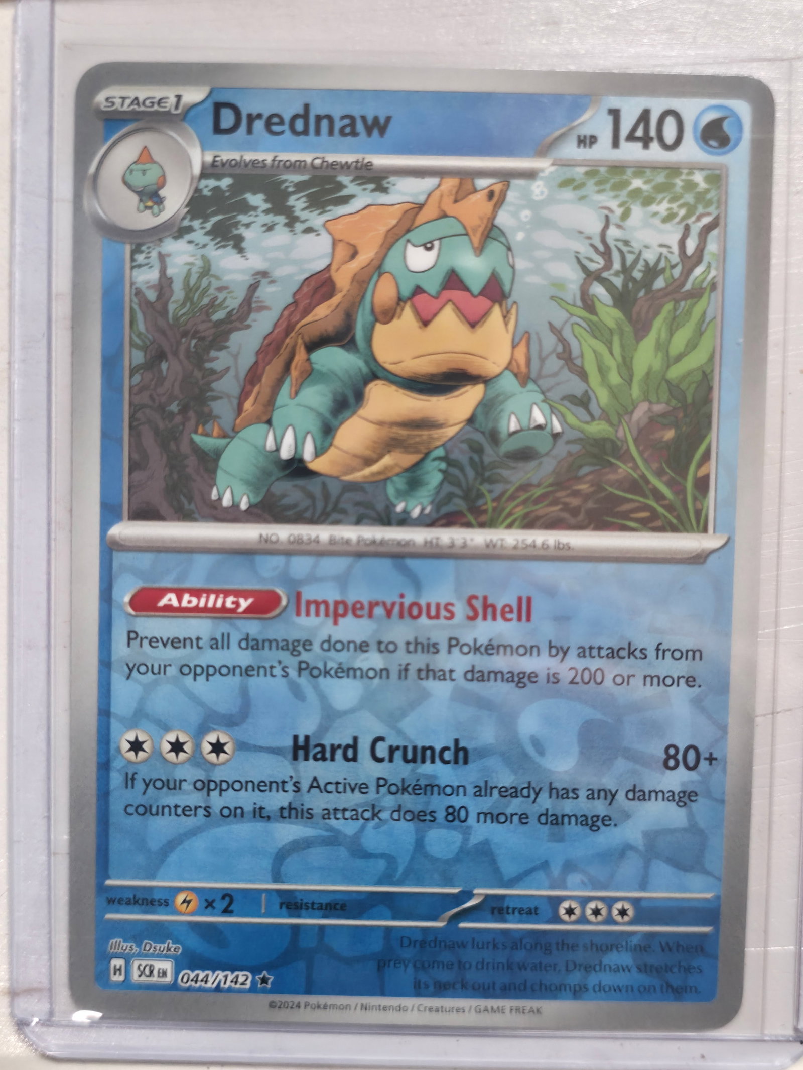 2024 Drednaw Stellar Crown 044/142 Reverse Holo: 2024 Drednaw Stage 1 Water Pokemon. Evolves from Chewtle. Stellar Crown set. Card number 044/142. Reverse holo with reflective pattern in text area. HP 140. Ability Impervious Shell. Attack Hard Crunc