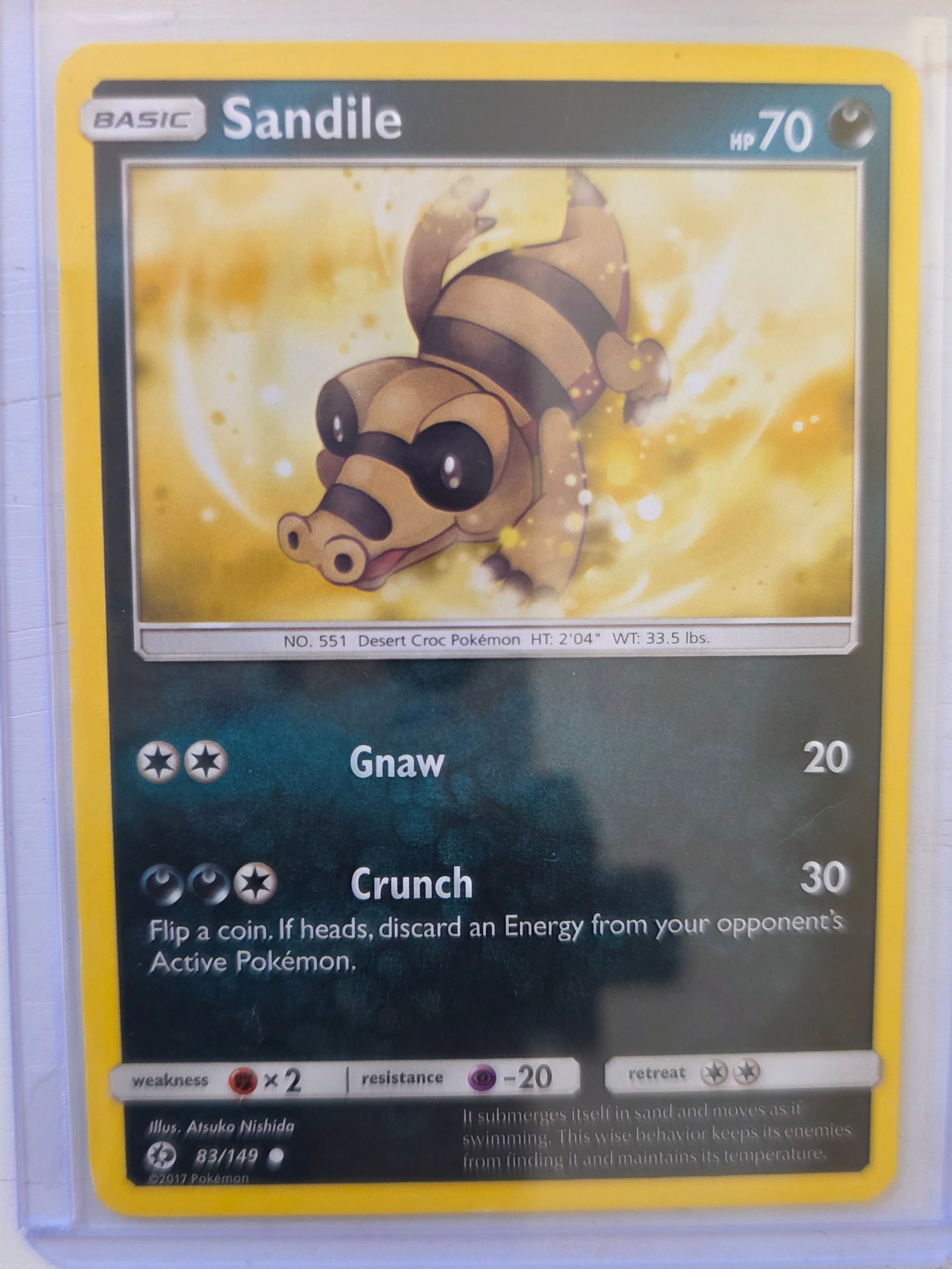 2017 Sandile Sun & Moon Base Set 083/149 Reverse Holo Pokemon Card: 2017 Pokemon Sandile reverse holo card numbered 083/149 from the Sun & Moon Base expansion set. Illustrated by Atsuko Nishida. Reverse holographic foil pattern across the card surface. Card stored in