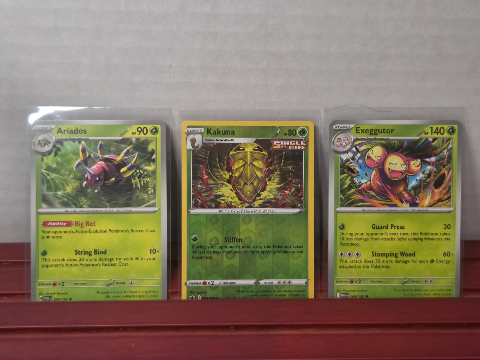 2021 Ariados 005/163 Kakuna Single Strike Exeggutor 005/132 Lot: Three card lot featuring Ariados, Kakuna Single Strike, and Exeggutor. Includes grass type Pokemon with bright modern artwork and a mix of standard and Single Strike styling. Cards are preowned and st