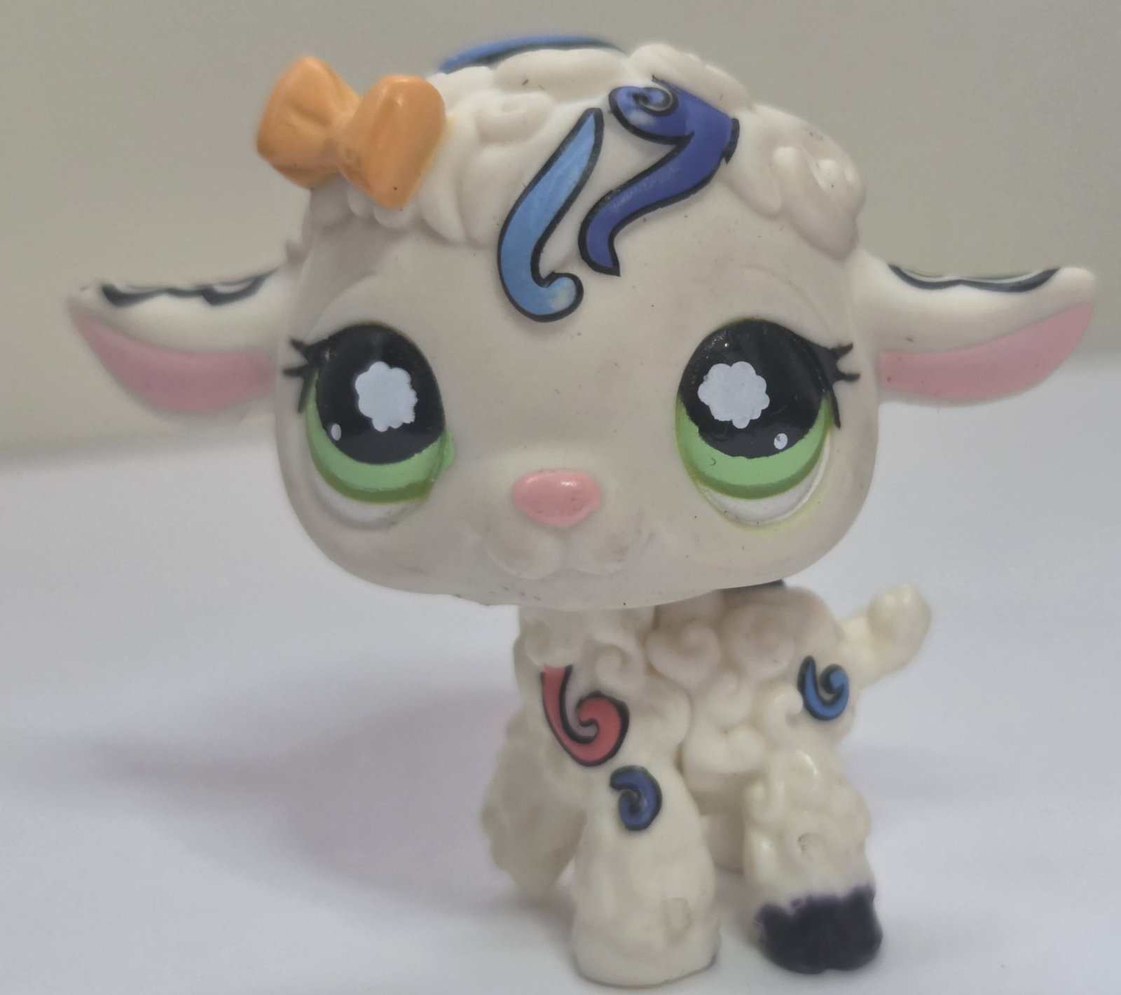 GEN 2 #1068 Lamb Postcard Pets Pink Magnet: Preowned Littlest Pet Shop Generation 2 lamb figure #1068 from the Postcard Pets series. Features a white body with green eyes, pink nose, orange bow detail, and colorful swirl pattern accents in blue