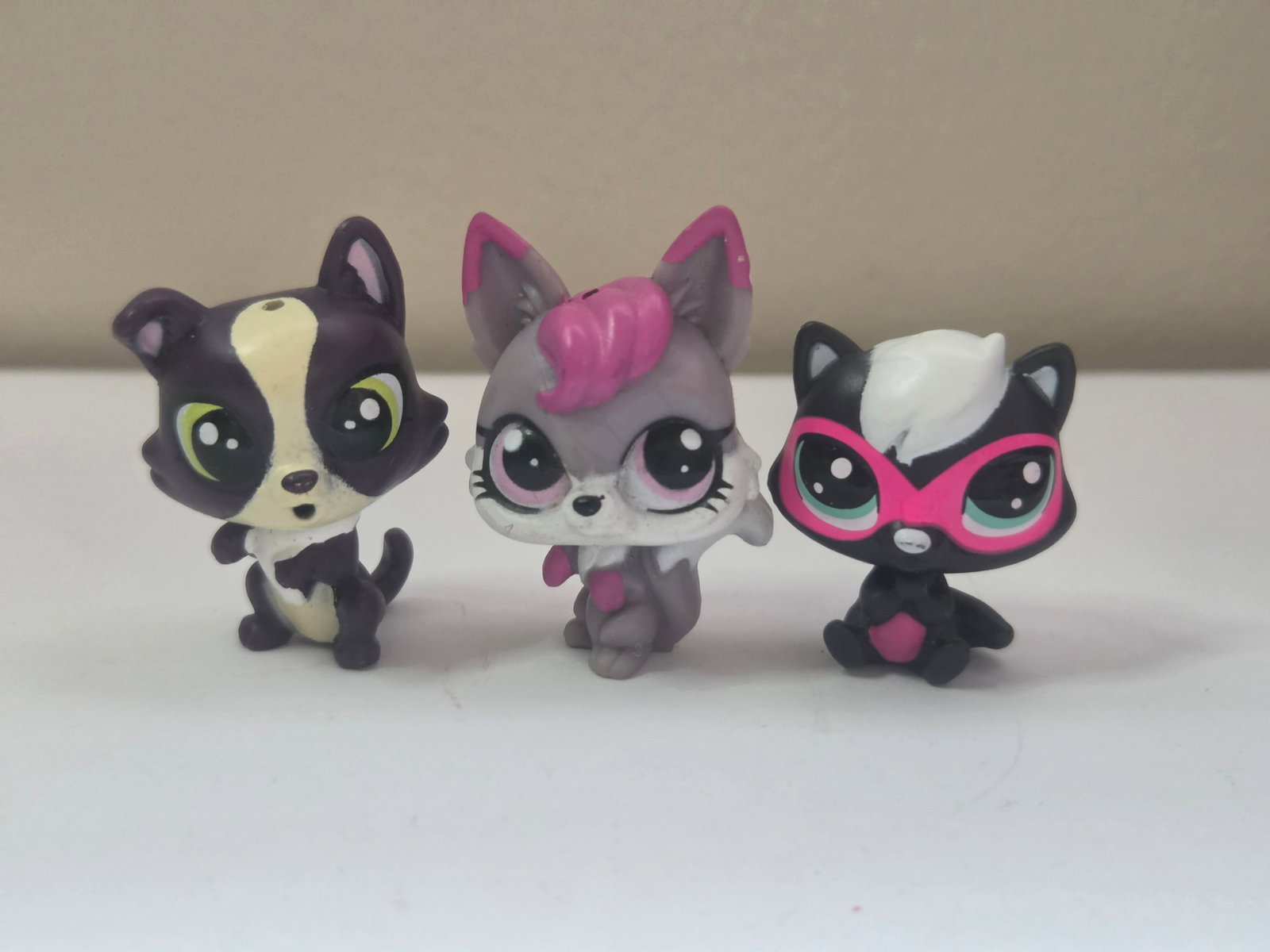 GEN 2 Raccoon Fox Skunk Lot Hasbro LPS Purple Gray Black: This lot includes three Littlest Pet Shop figures by Hasbro featuring a purple and cream raccoon, a gray fox with pink hair detail, and a black skunk with a white stripe and bright pink glasses markin