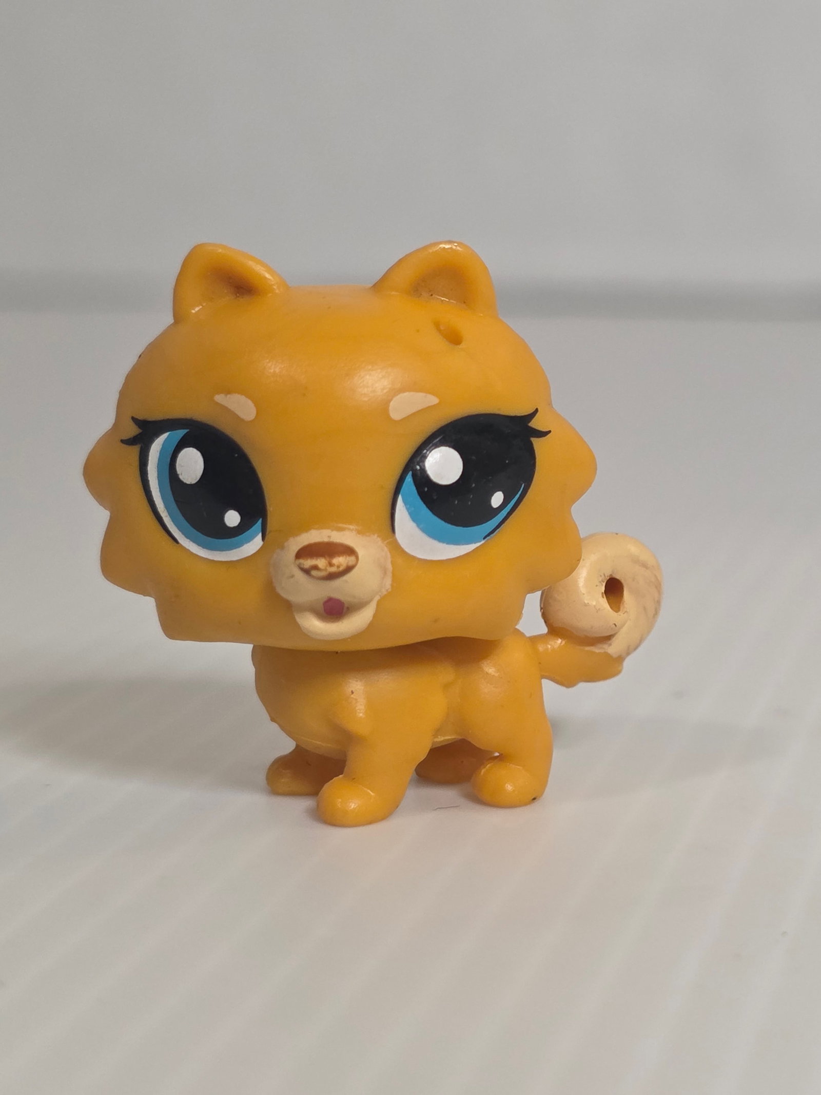 GEN 2 Pomeranian Dog Orange Tan Blue Eyes LPS: This Littlest Pet Shop figure features a small orange tan Pomeranian dog with blue eyes and curled tail. It is an authentic Hasbro LPS figure from the G2 era. This piece shows noticeable play wear inc