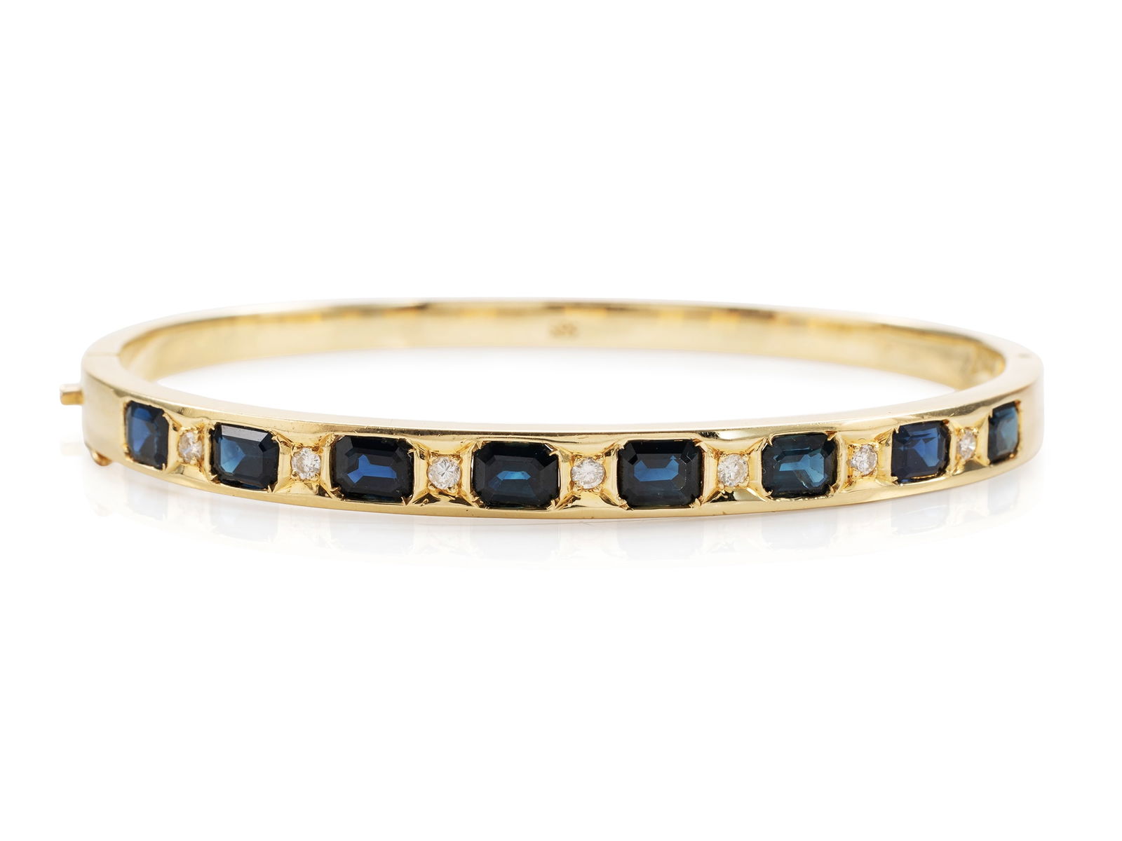 Sapphire and Diamond Bangle in Yellow Gold: Sapphire and Diamond Bangle in Yellow GoldElegant yellow gold bangle, unhallmarked, tested to 585 fineness. Set within the bangle are eight dark blue emerald-cut sapphires totaling approximately 4.80