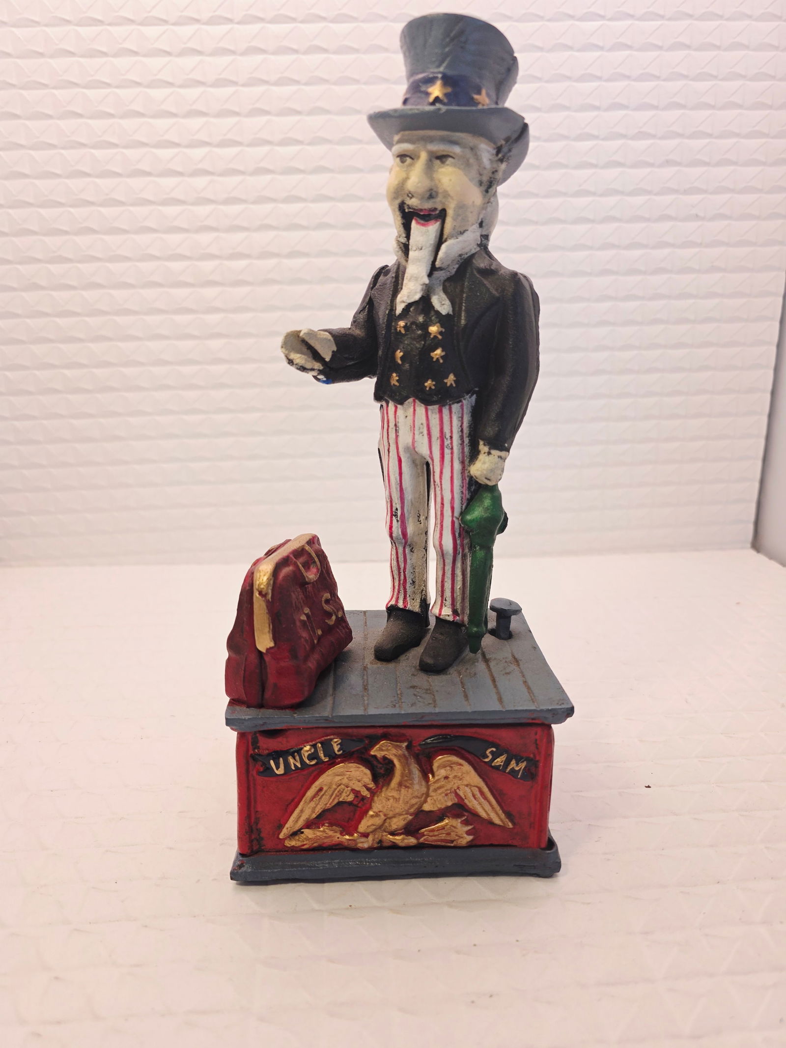 Uncle Sam cast iron mechanical coin bank: vintage-style reproduction Uncle Sam cast iron mechanical coin bank. Mechanism: When a coin is placed in Uncle Sam's hand and a lever is pressed, he lowers his hand to drop the coin into his satchel.