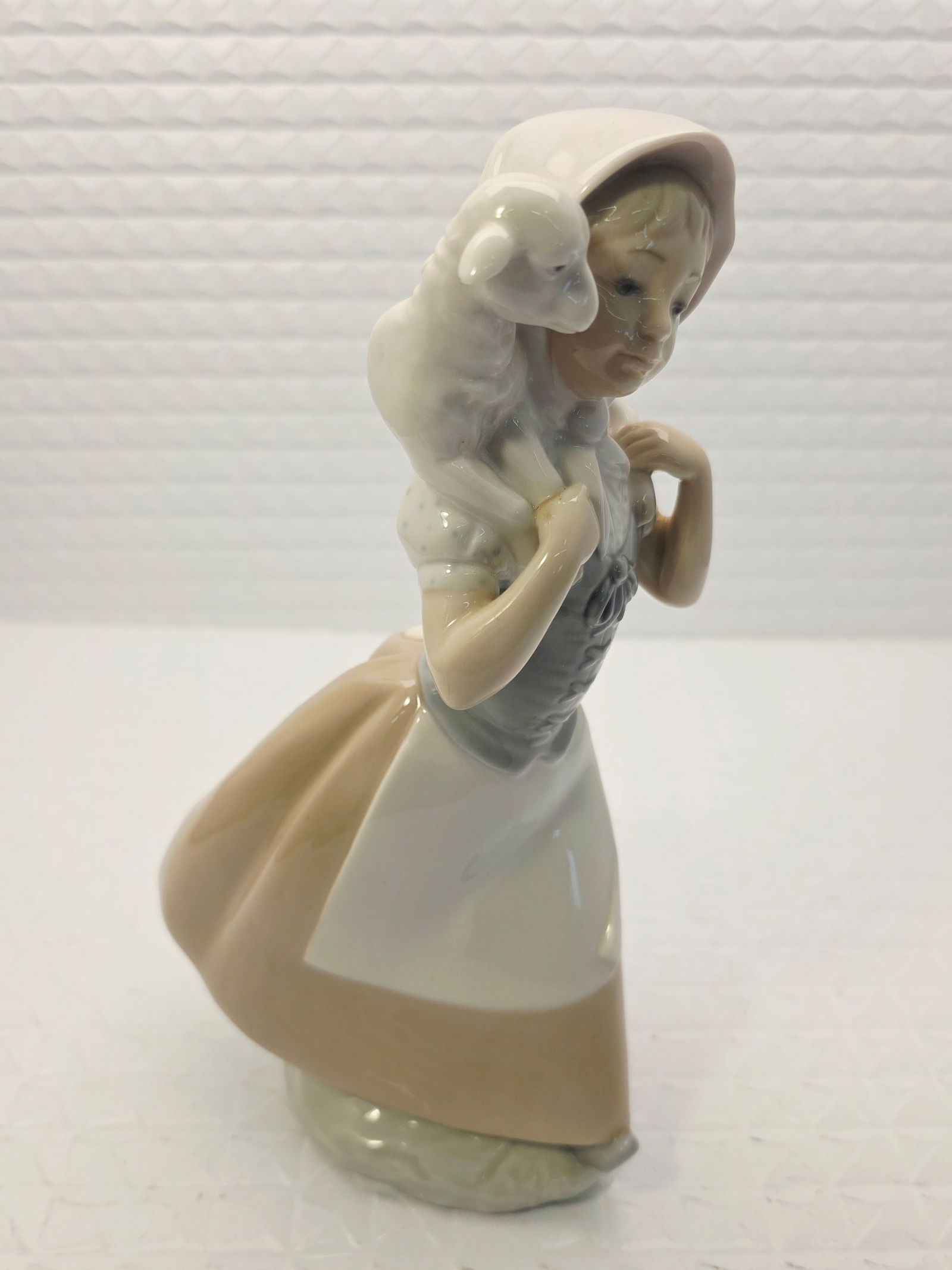 NAO by Lladró porcelain figurine "Good Shepherdess": NAO by Lladró porcelain figurine titled "Good Shepherdess" (model #238). It depicts a young girl in a bonnet and dress carrying a small lamb across her shoulders. The figurine is handmade in Spain an