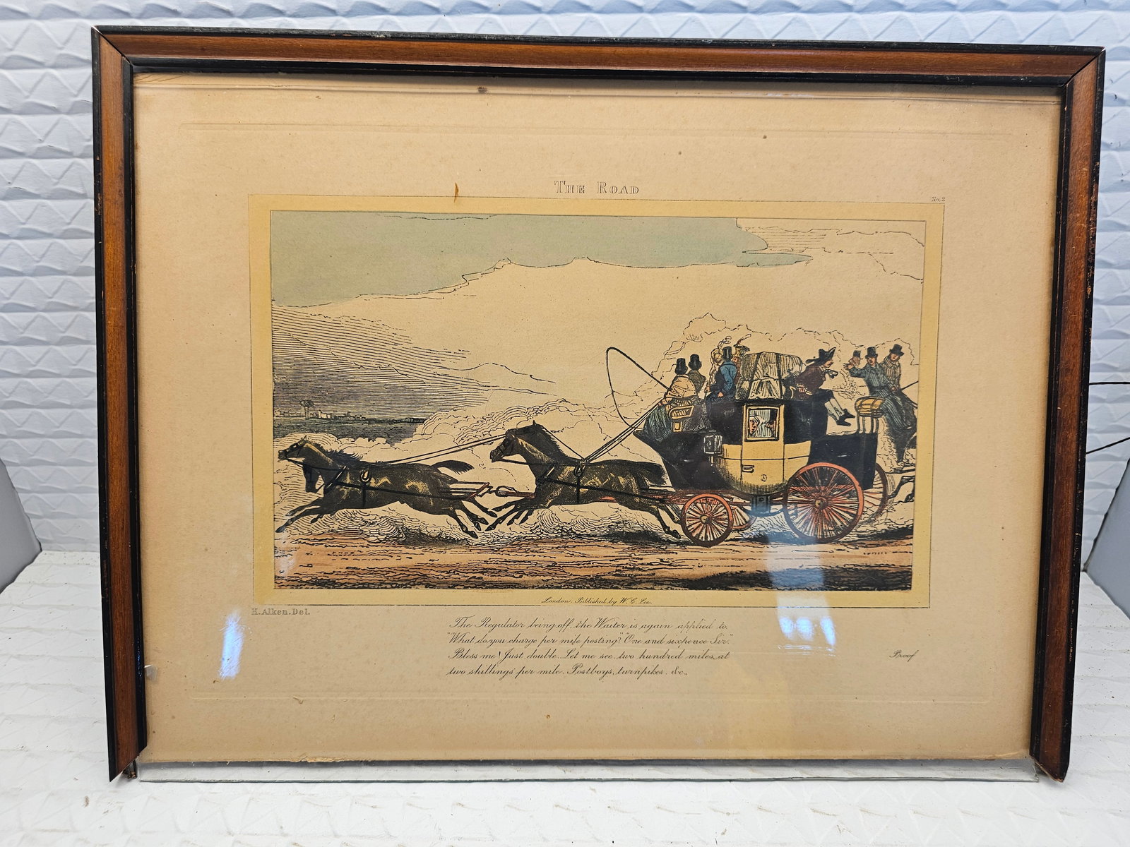 hand-colored engraving titled "The Road": hand-colored engraving titled "The Road" after Henry Thomas Alken, likely published in the early 19th century.Artist & Subject: The print depicts a horse-drawn stagecoach scene, a common subject for B