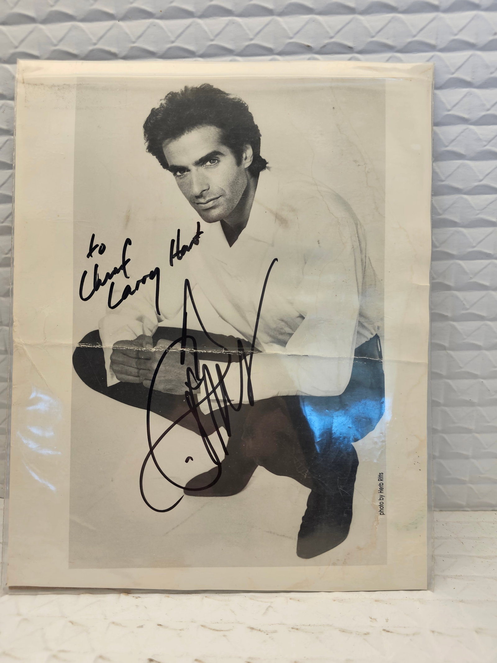 black and white photograph of renowned illusionist David Copperfield.The photo appears to be a: black and white photograph of renowned illusionist David Copperfield.The photo appears to be a promotional headshot signed by Copperfield himself.It includes a personalized inscription, "To Chief Larr