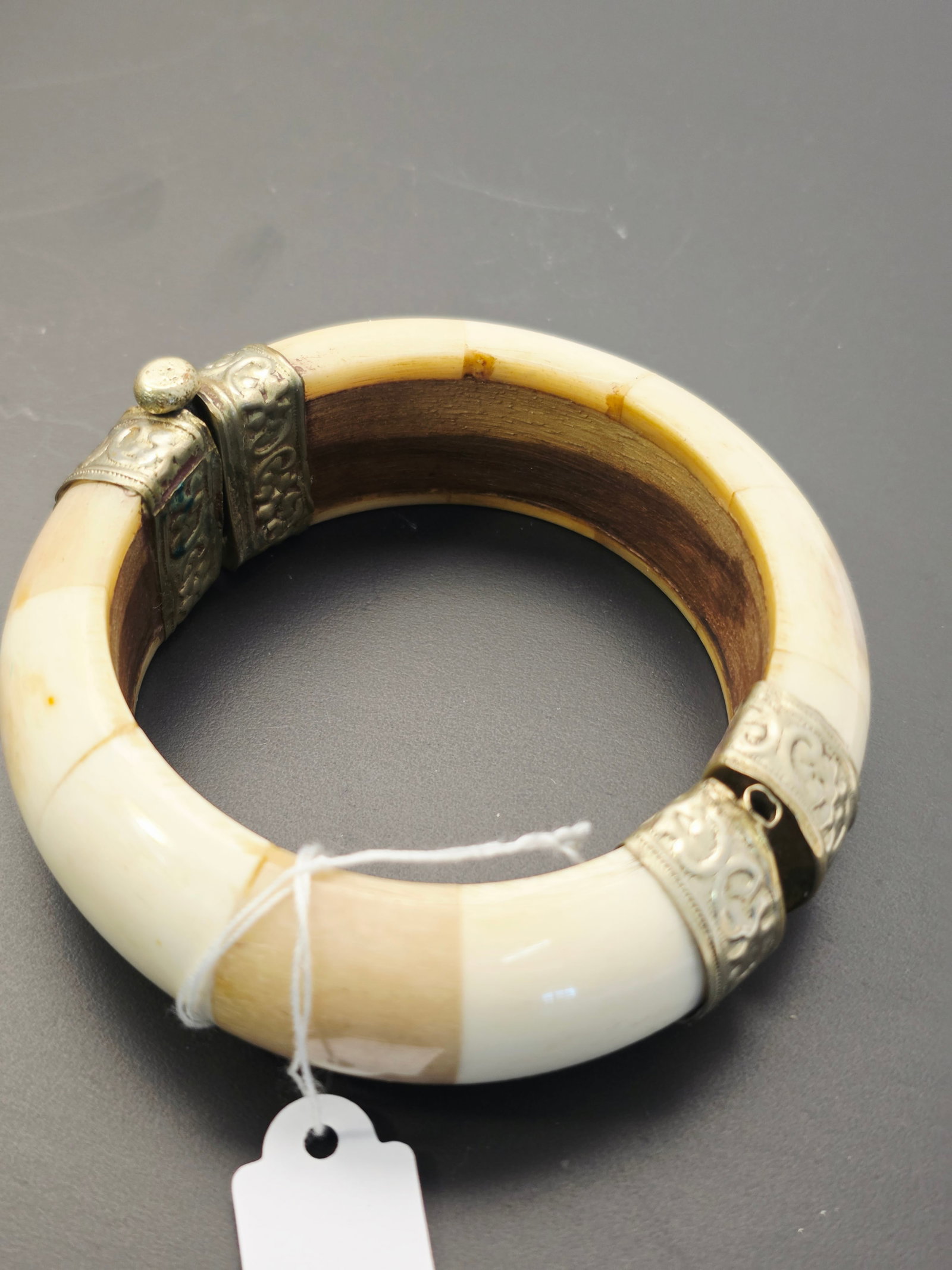 vintage bone pull pin hinged bangle bracelet: This is a vintage bone pull pin hinged bangle bracelet.The bracelet features segmented, cream-colored natural material, often described as bovine bone or horn, set with decorative metal hardware.It in