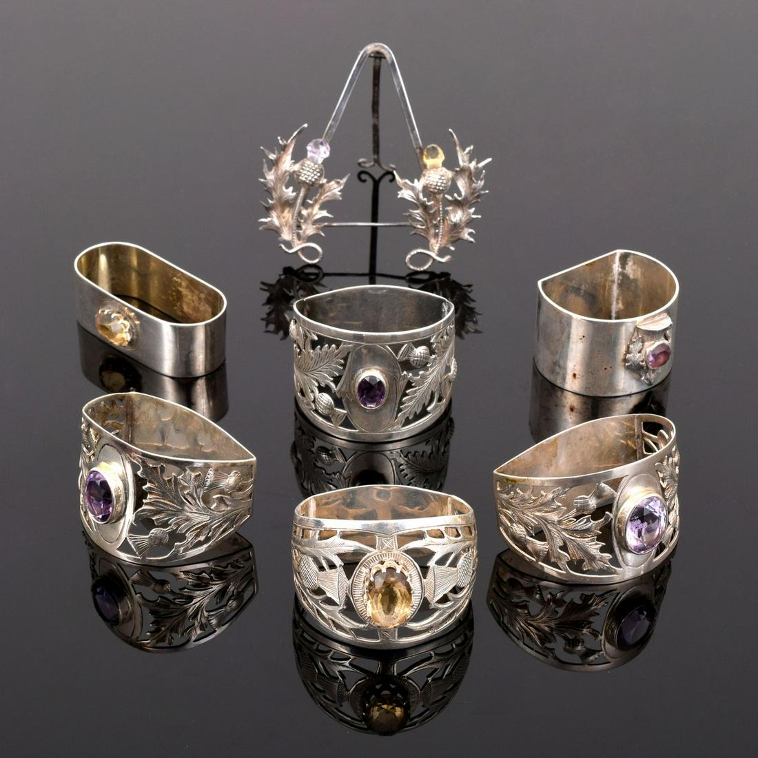 6 Sterling Silver Napkin Rings & 1 Place Card Holder: Artist/Designer; Manufacturer: J. Cook & Sons Ltd., various Marking(s); notes: marking(s) Country of origin; materials: England; sterling silver, gemstones Dimensions (H, W, D): largest napkin ring: 1