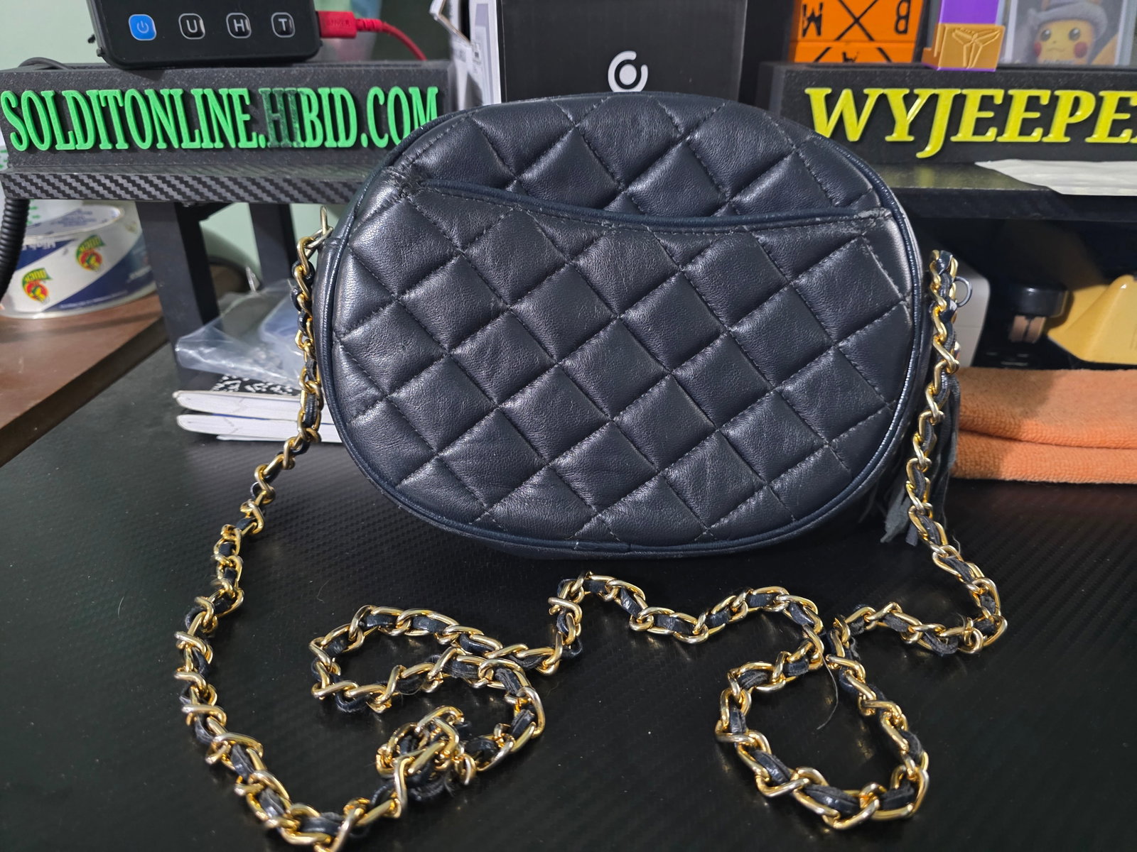 quilted crossbody, blue exterior,gold chain strap,and a tassel zipper pull: The quilted crossbody bag in black with a gold chain strap and tassel zipper pull is a stylish and geometrically sleek accessory for women. Made from faux leather, this small rectangular bag features 
