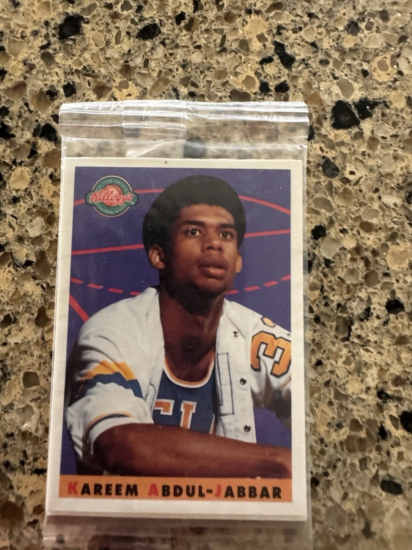 1993 Kellogg’s - Kareem Abdul-Jabbar College Greats Postercard Sealed In Package: The 1993 Star Pics Kellogg's College Greats Postercards featuring Kareem Abdul-Jabbar is a standard-sized trading card made of card stock. This original card from the NCAA set showcases the basketball