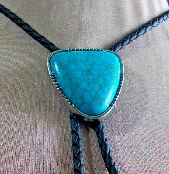 Description western bolo tie Triangular turquoise coloured stone on black cord: western bolo tie Triangular turquoise coloured stone on black cord